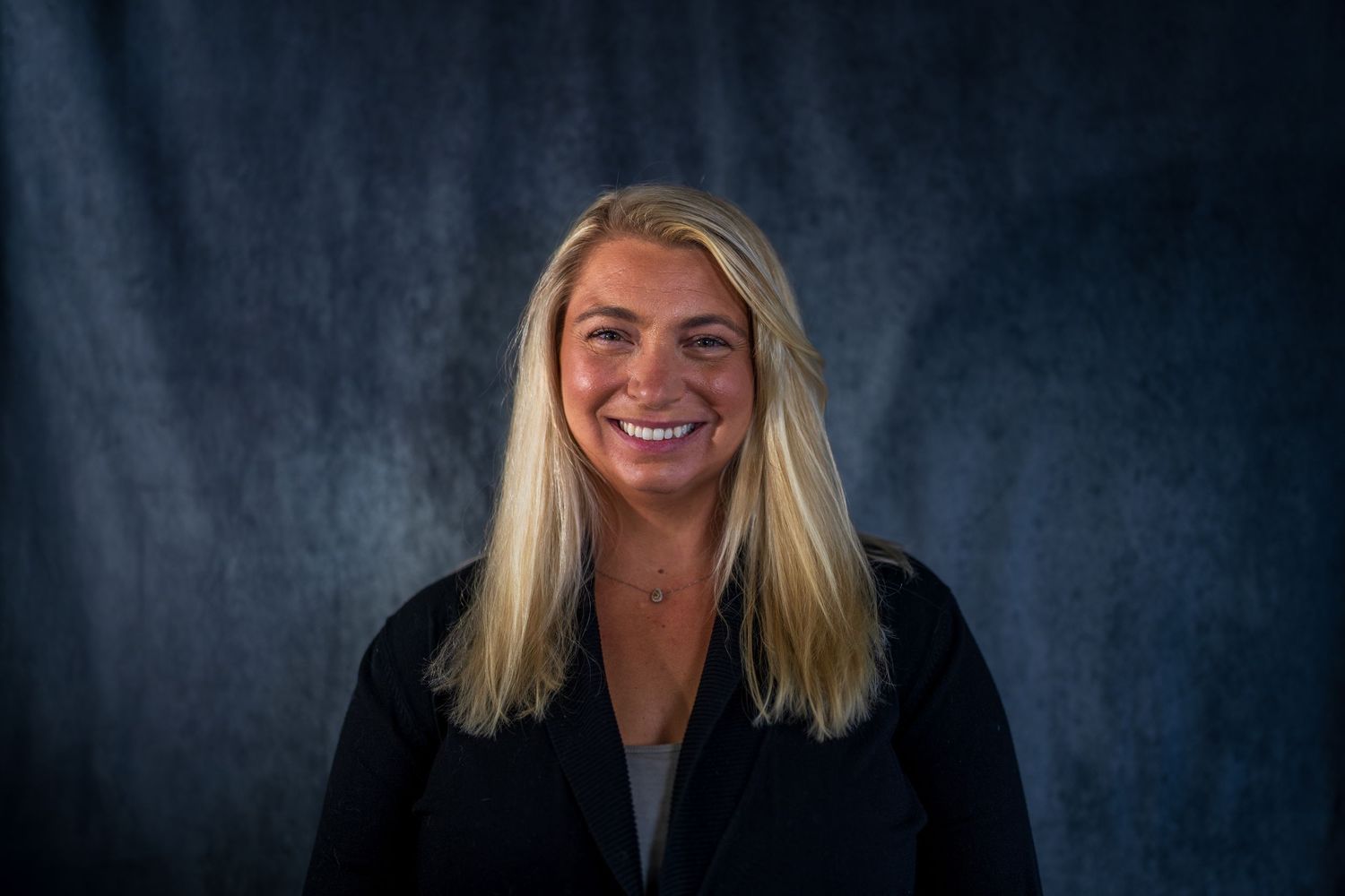 Professional portrait series showing confident smile against dark backdrop.