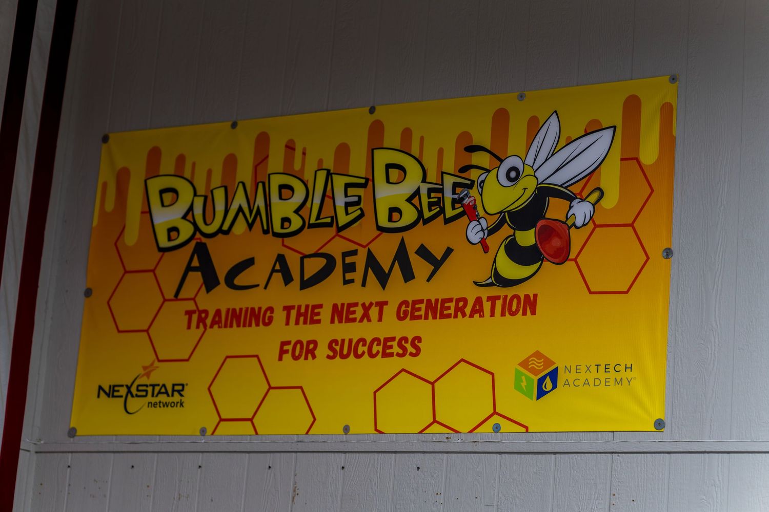 Row of yellow Bumble Bee Plumbing banners displayed on wall showing company branding.