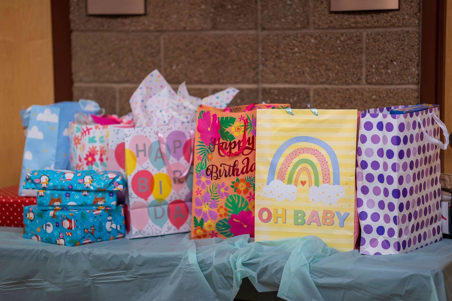 Colorful birthday and baby shower gift bags including Happy Birthday and Oh Baby designs displayed on a table.