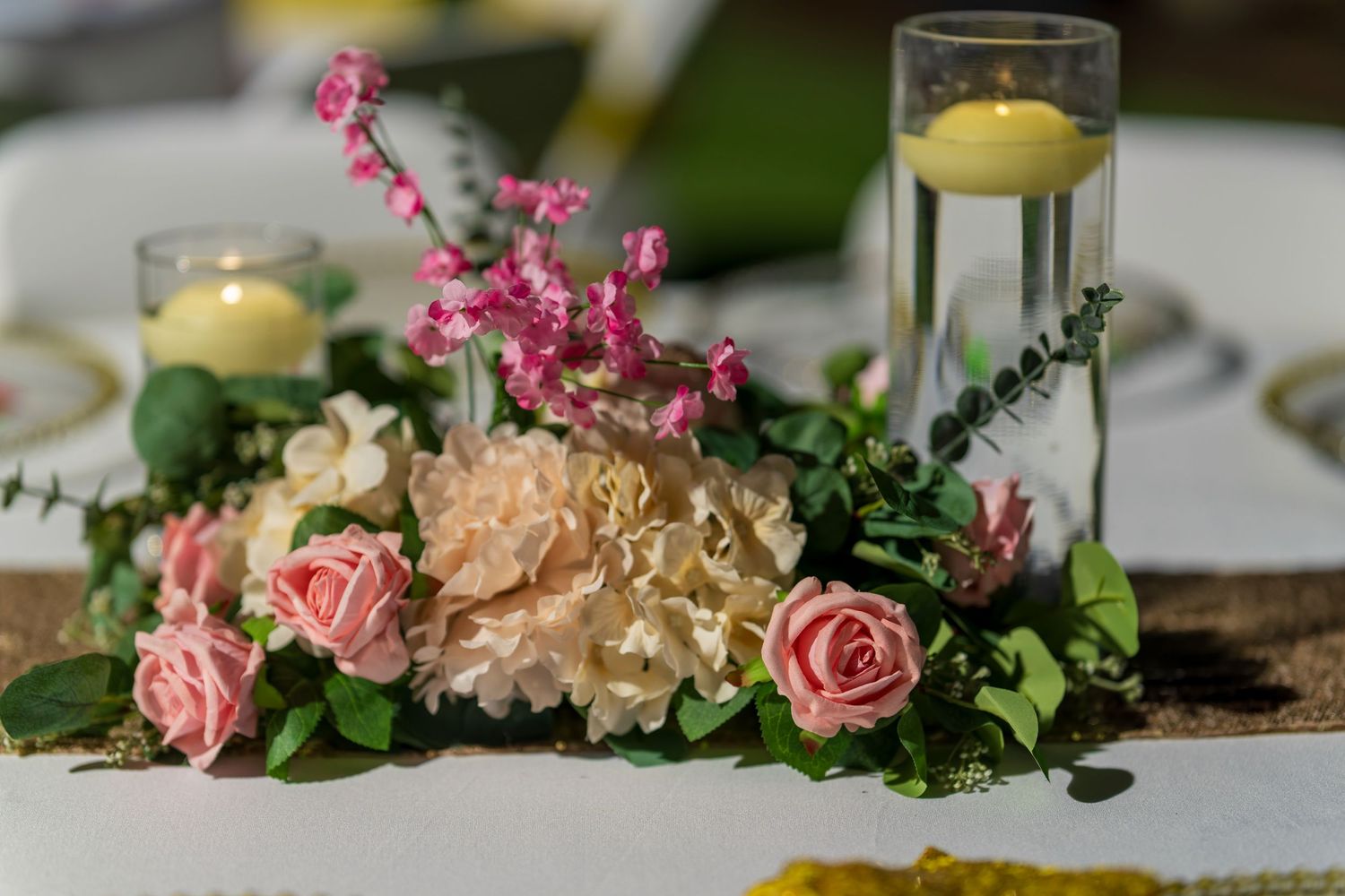 Elegant table decor with pink roses and candles at a formal event.