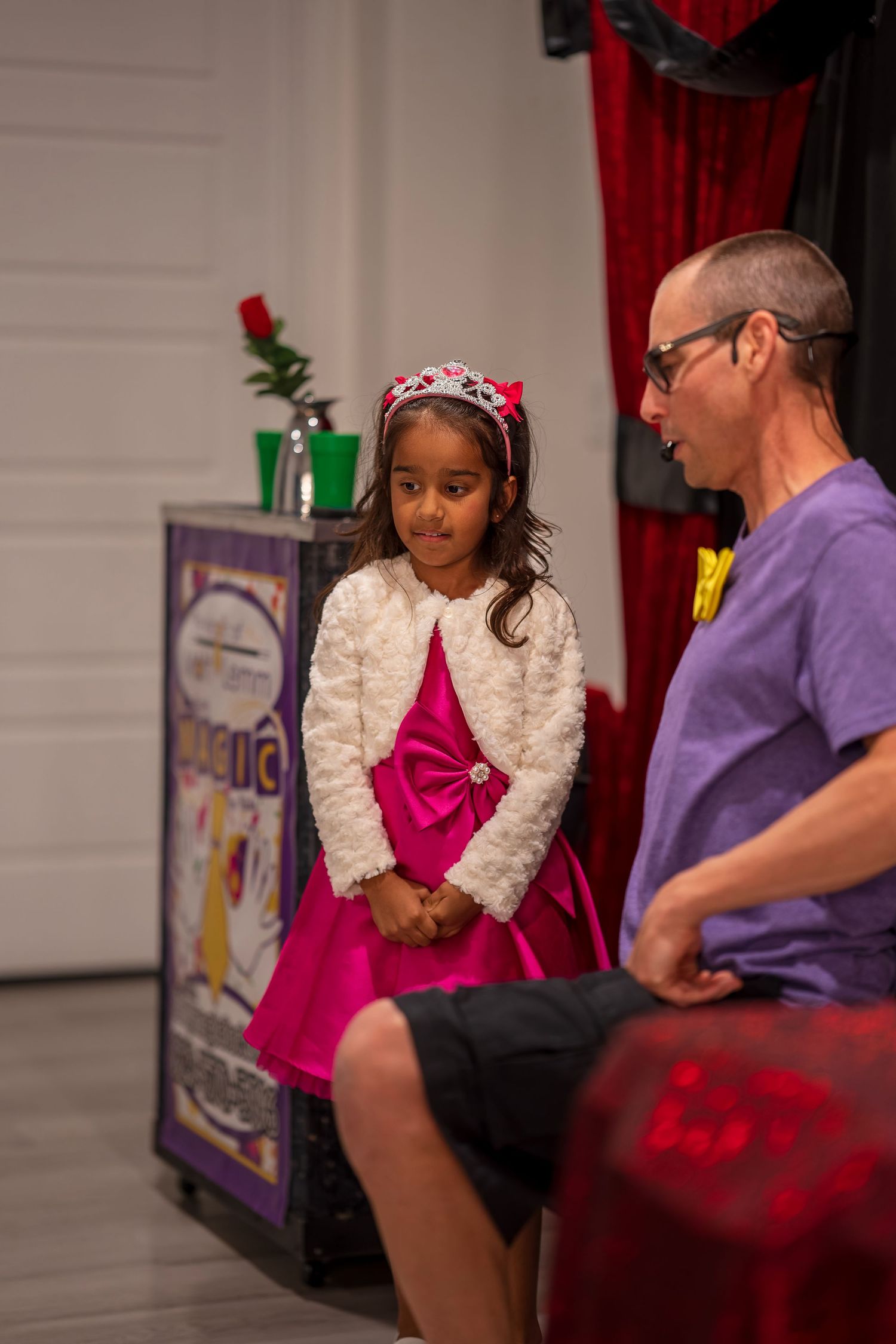Magic show performance scene with red curtain backdrop and stage props.