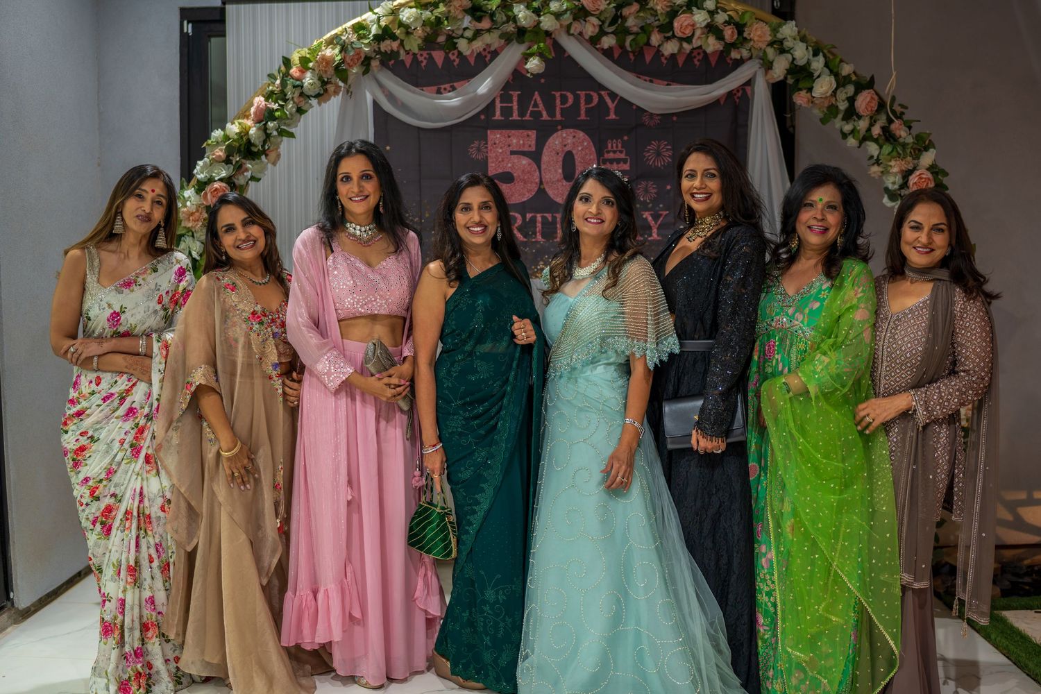 Group portrait of attendees wearing elegant ethnic wear and western formal dresses.