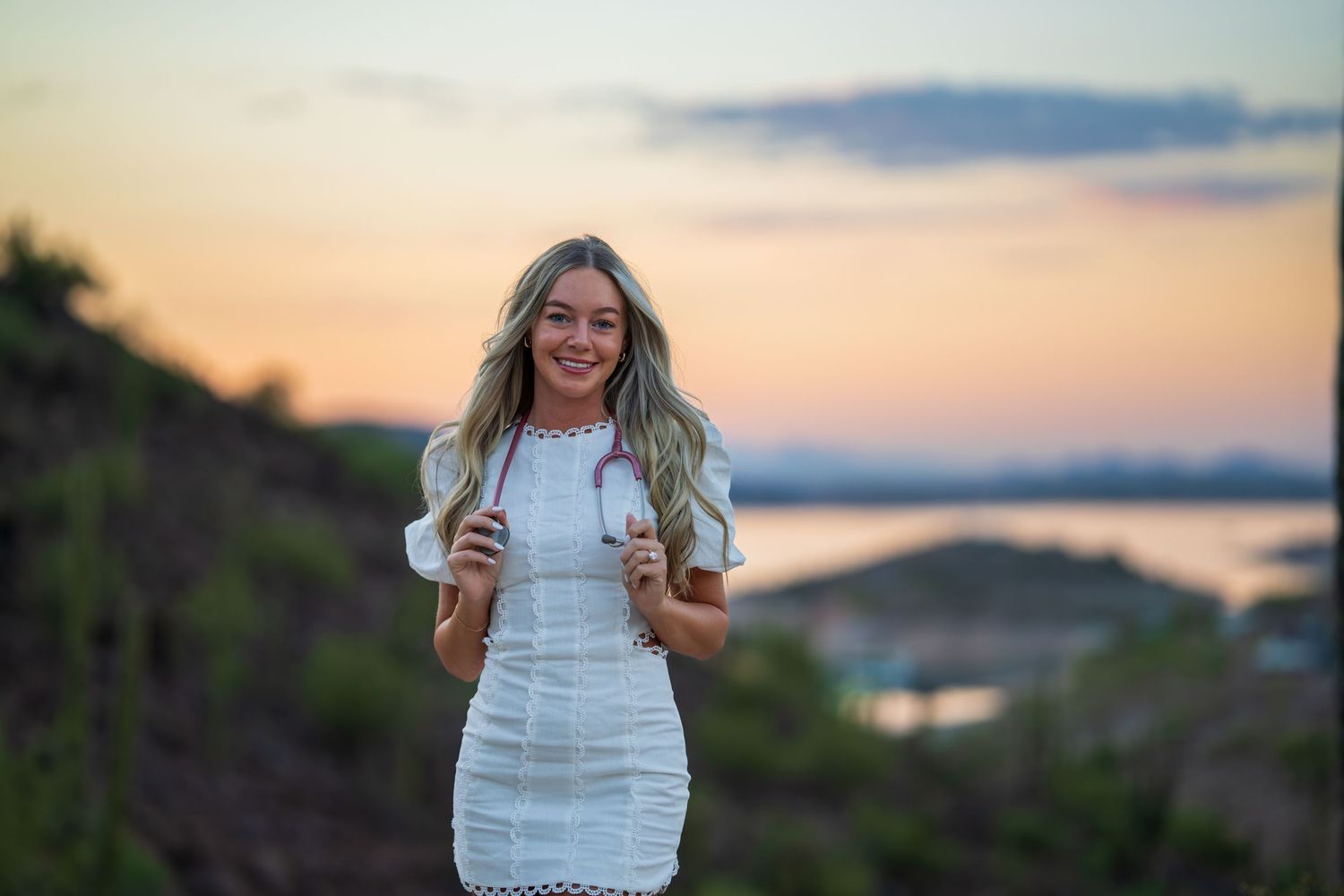 Desert photoshoot featuring white mini dress against mountain landscape at sunset.