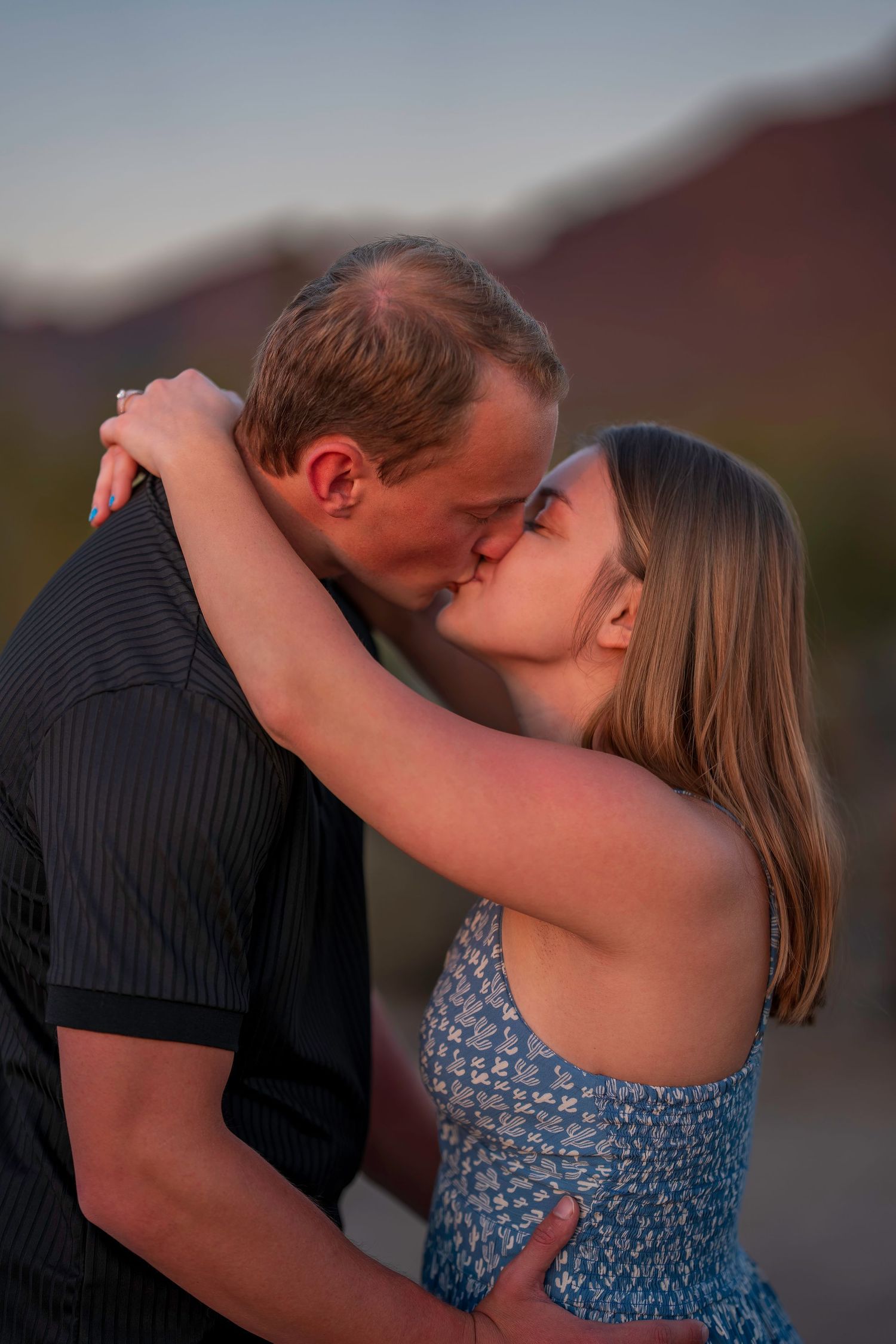 A couple shares a tender kiss during golden hour in the desert.