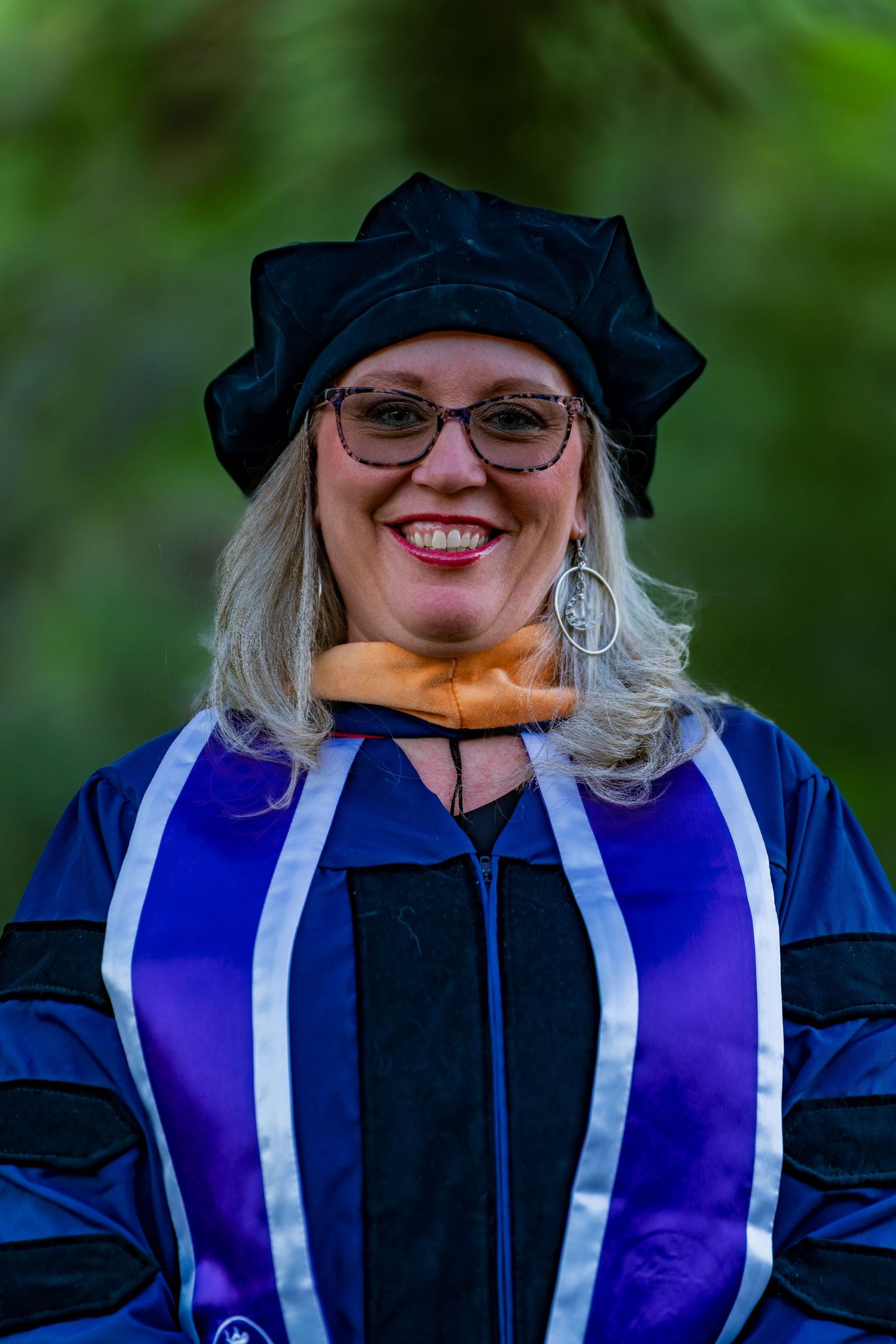 Graduate wearing academic cap and gown smiling during graduation ceremony.