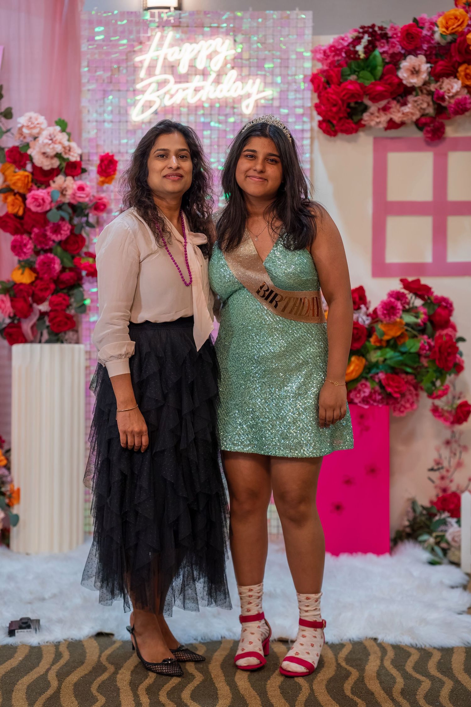 A festive celebration with pink floral decorations and a neon sign against a decorated wall.