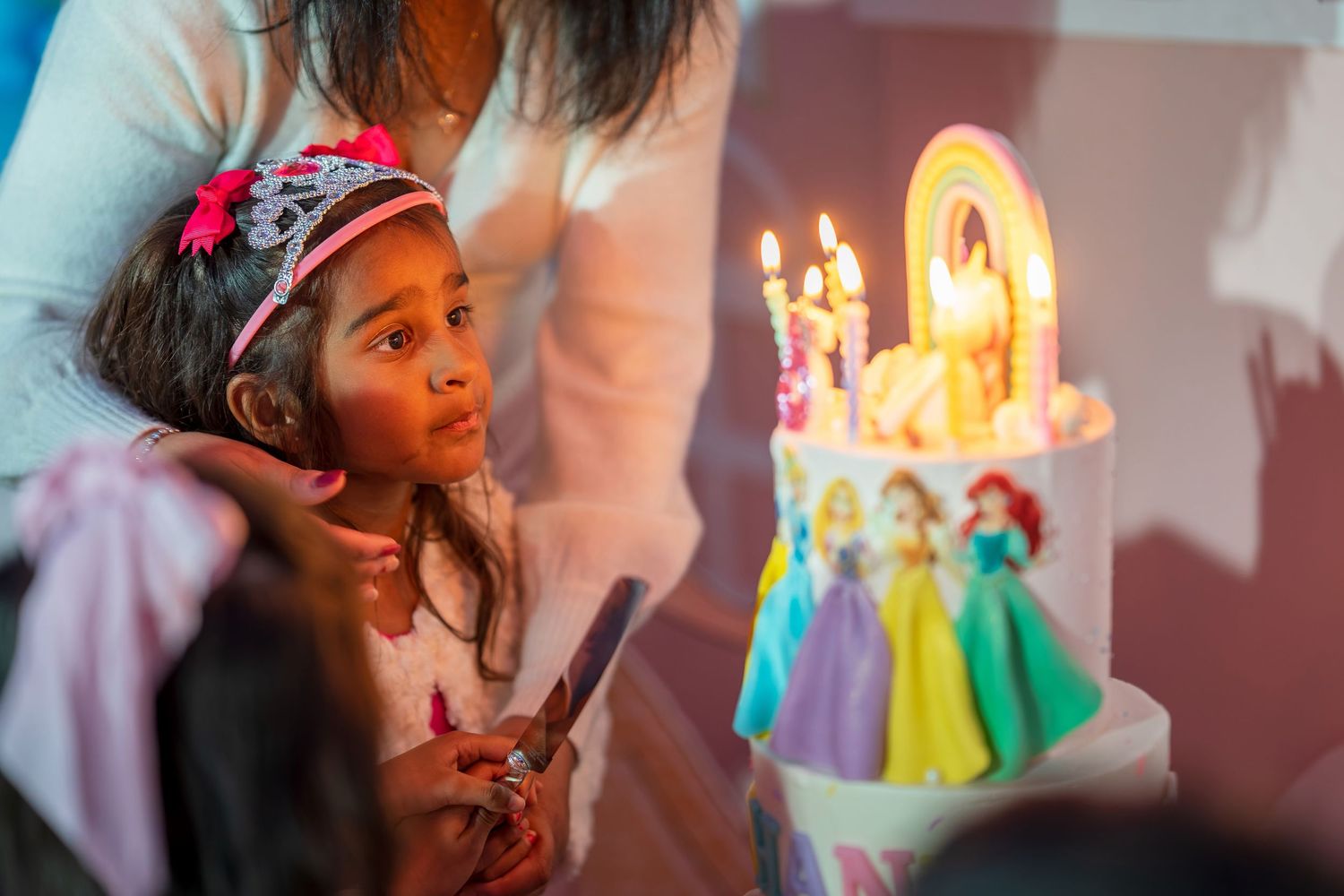 A magical birthday moment with lit candles on a rainbow-themed cake.
