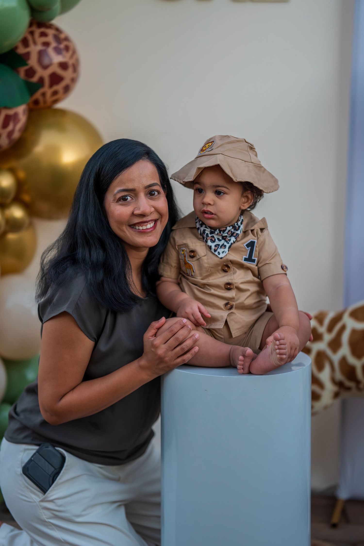 A safari-themed first birthday celebration with balloon decorations and a giraffe print backdrop.
