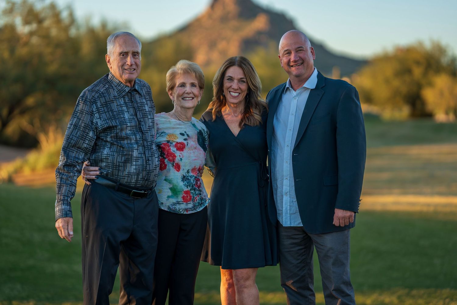 Family portrait session outdoors at sunset with mountain backdrop and natural lighting.