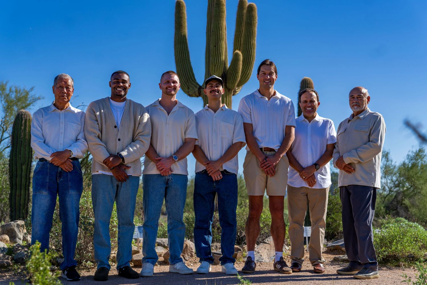 Group photo in desert landscape with mountains and saguaro cacti in the background.