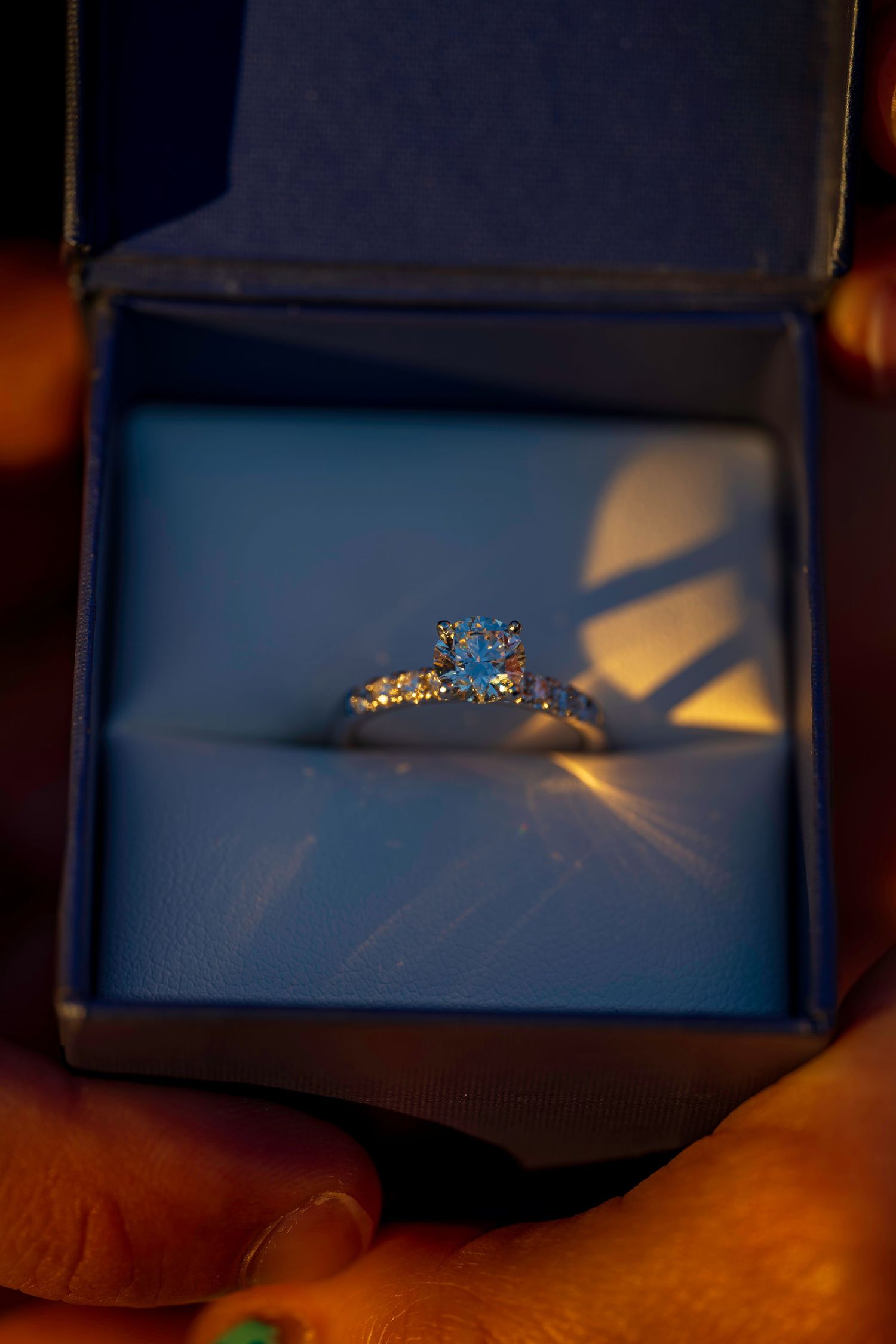 Diamond engagement ring with blue center stone in blue velvet box.