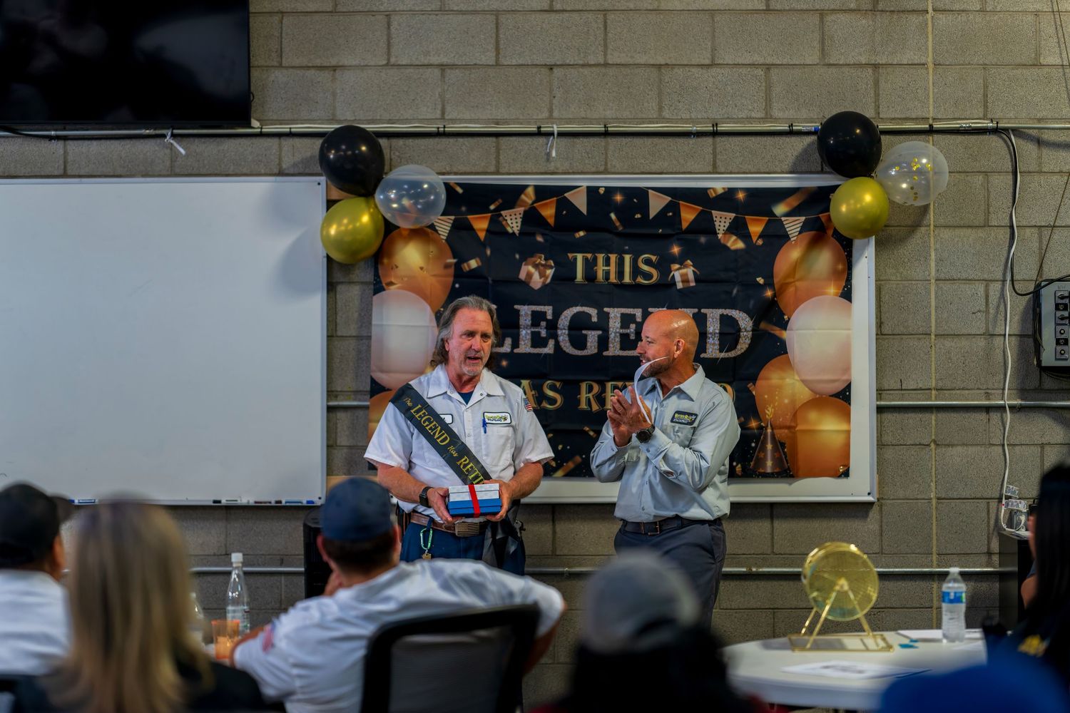 Award ceremony presentation with banner and balloons at company event.