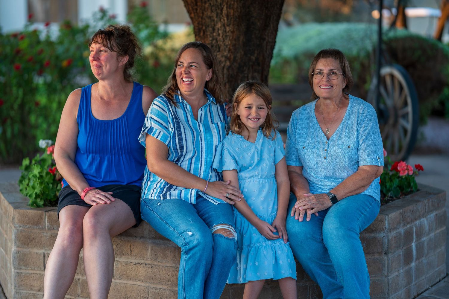 Group portrait of family members sitting together outdoors in matching blue attire.