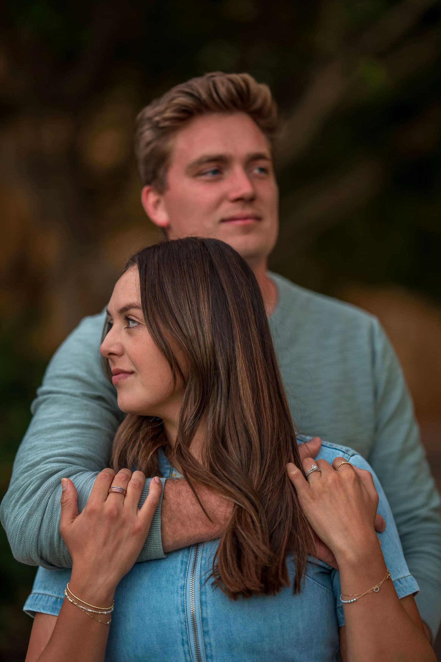 Playful couple in matching blue outfits posing together outdoors.