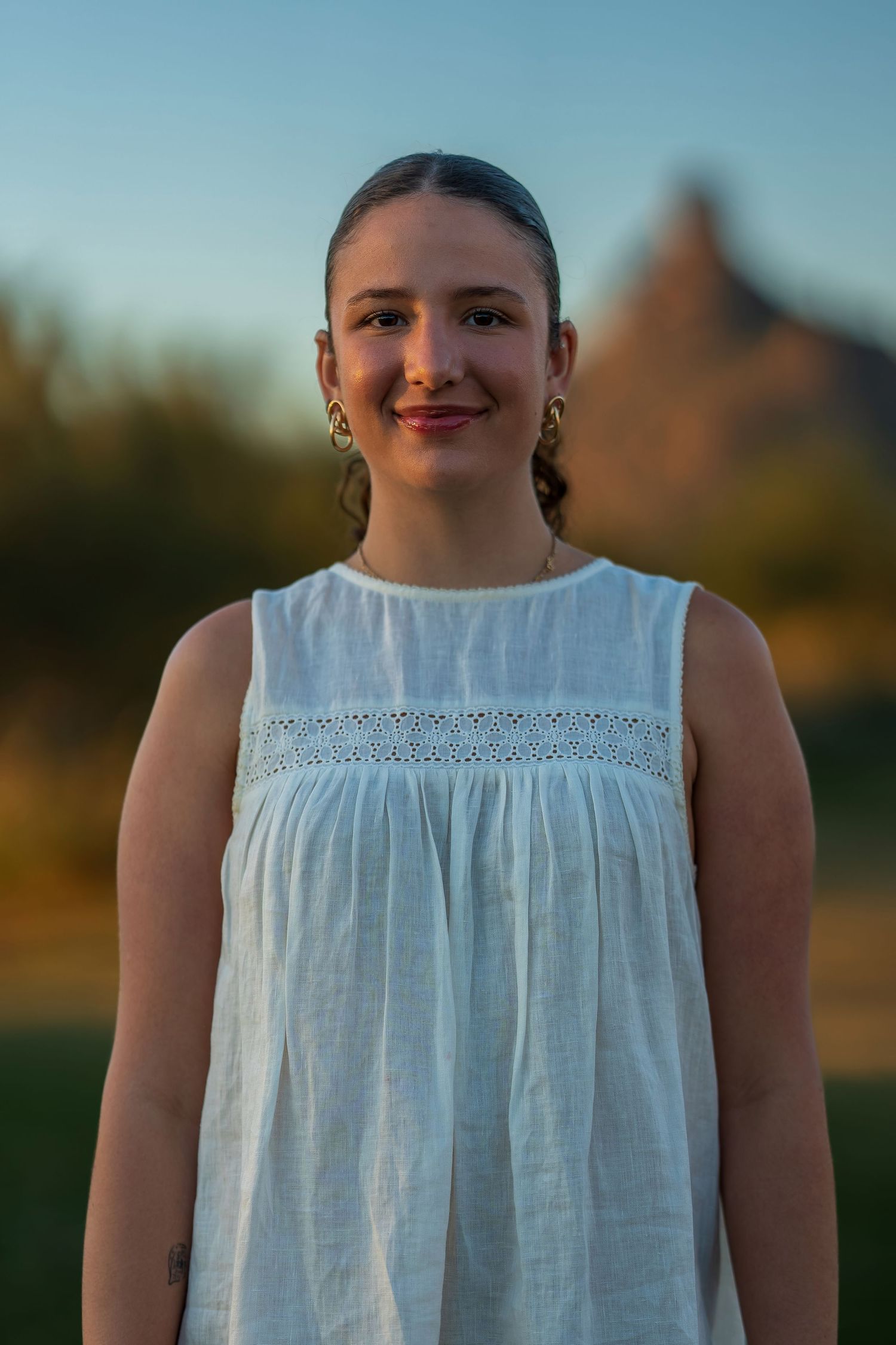Close-up portrait of person in white summer dress against evening sky.