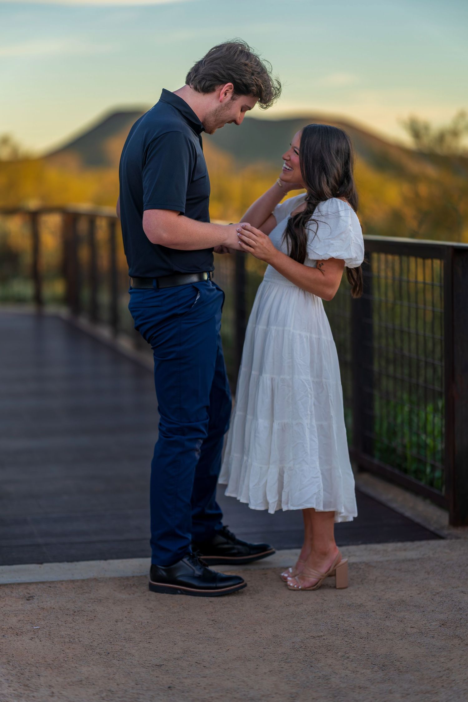 A couple's feet are visible during a special moment on an outdoor observation deck at sunset.