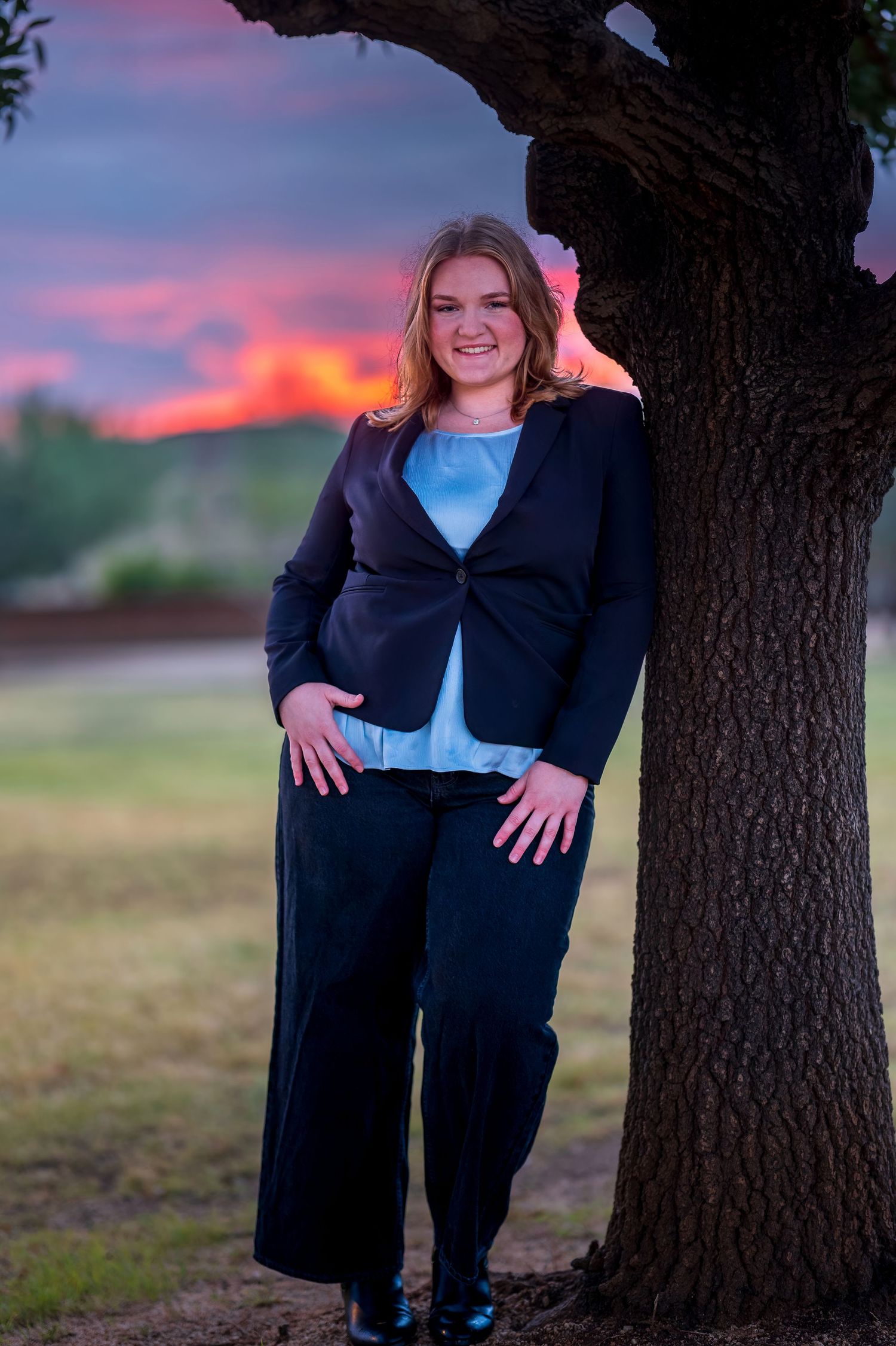 Outdoor business portrait with dramatic sunset sky and tree backdrop.