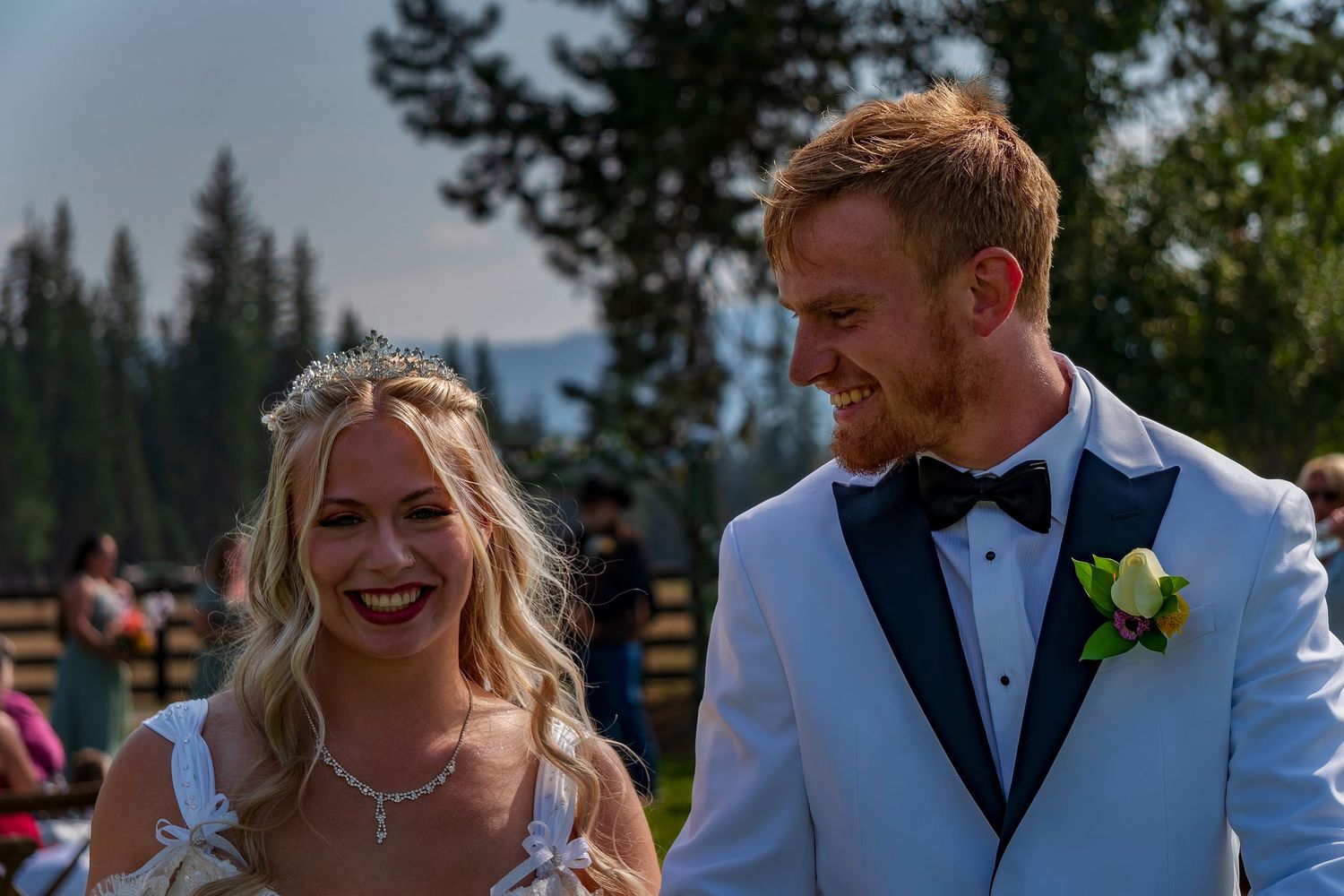 Newlyweds share a candid laughing moment during their mountain wedding ceremony.
