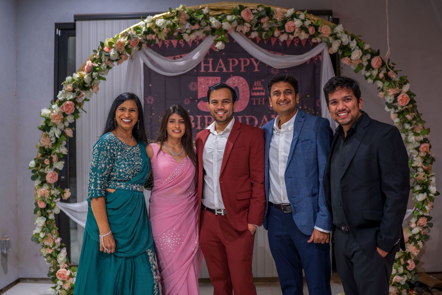 Group of guests in formal attire posing together at a special celebration event.