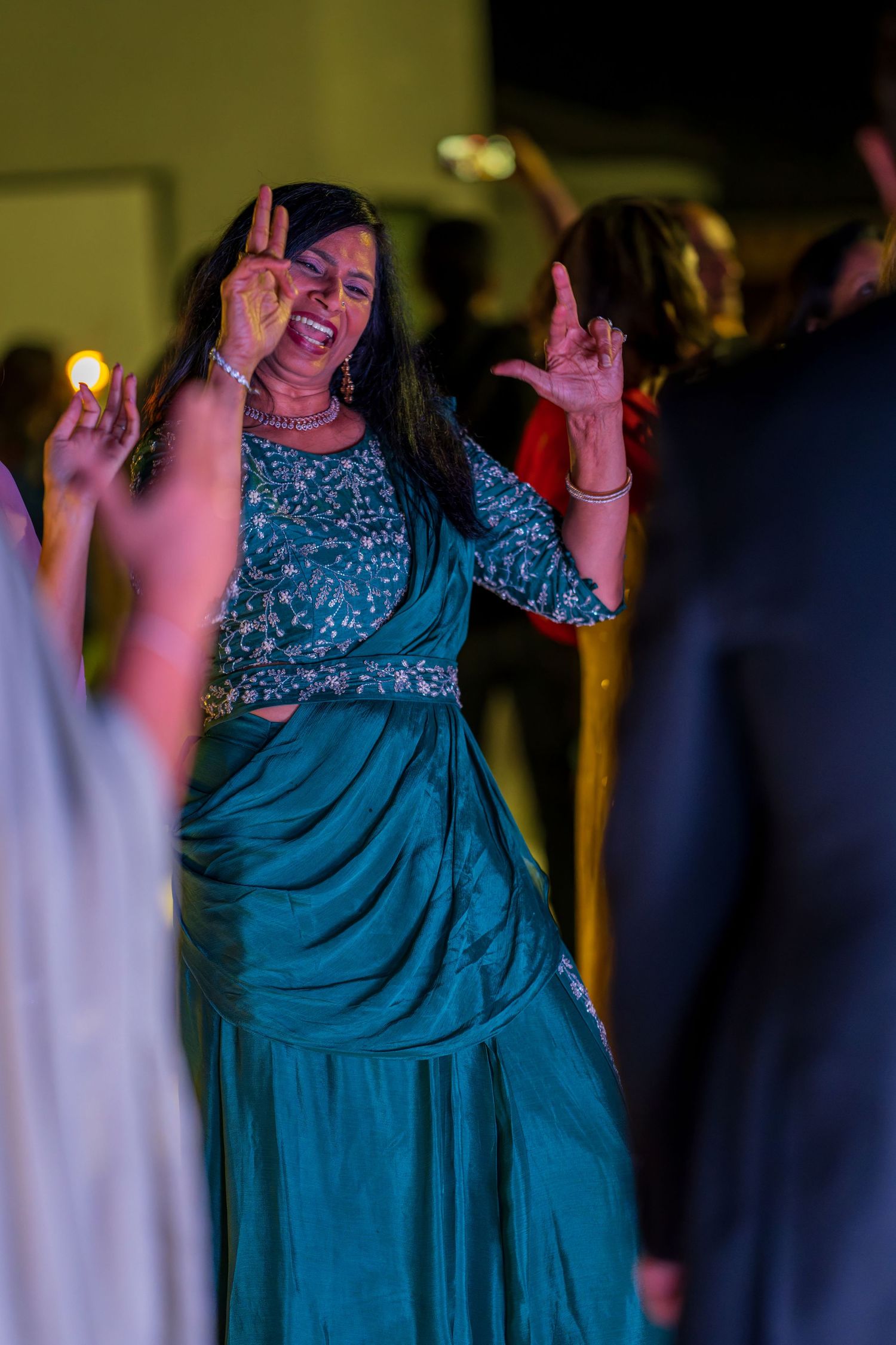 People dancing in elegant blue and sequined outfits at a festive celebration.
