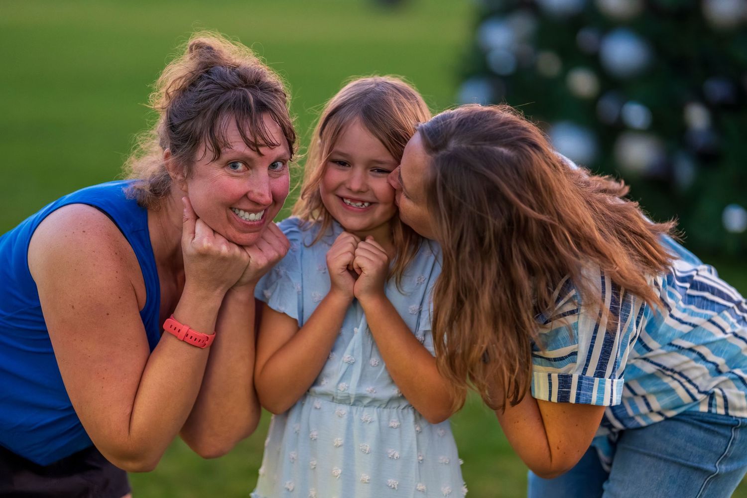 Friends sharing an intimate moment together on a grassy field at sunset.
