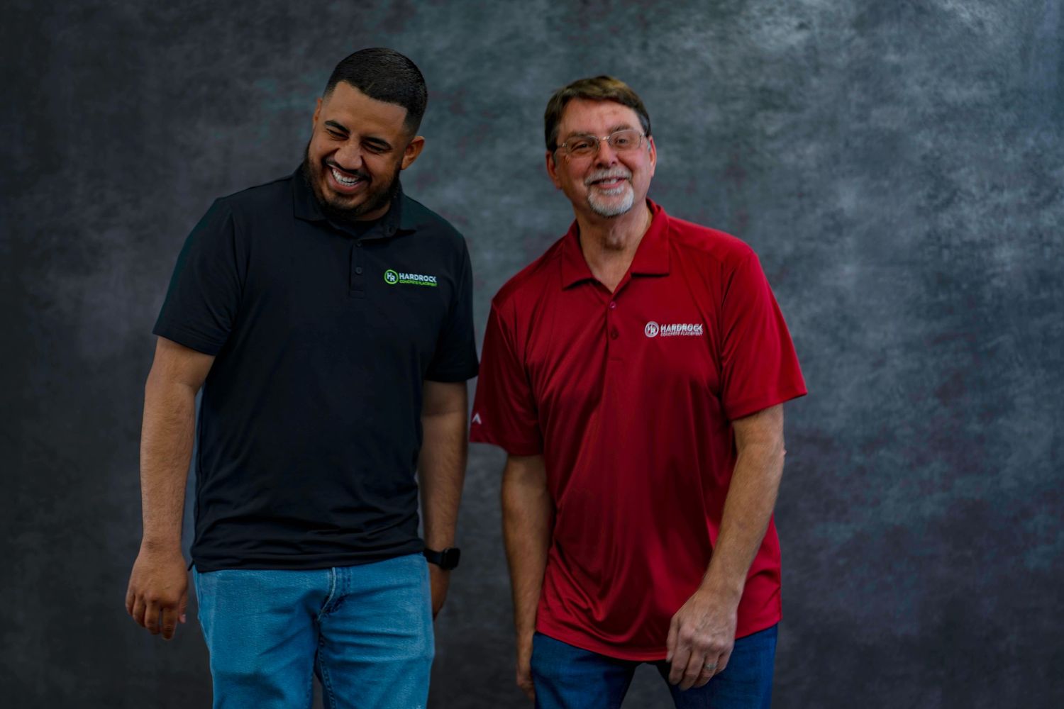 Two team members wearing contrasting black and red polo shirts pose for company photo.