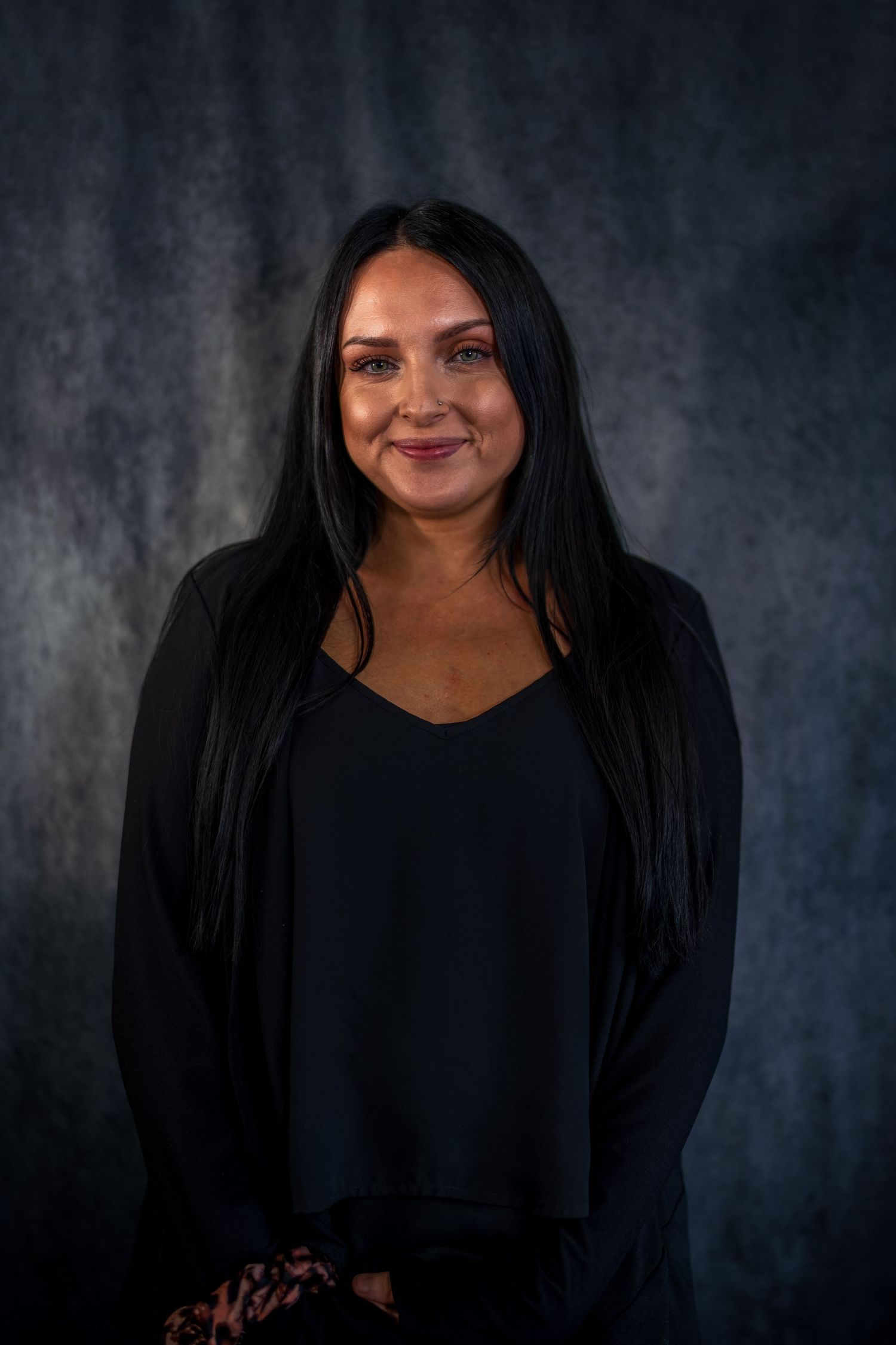 Professional portrait of woman in black top against dark gray background.