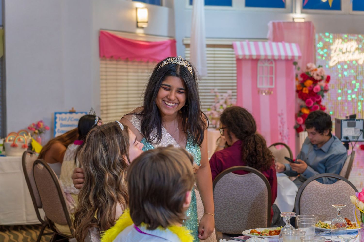 Party guests gathered around tables decorated with pink and white party decor.