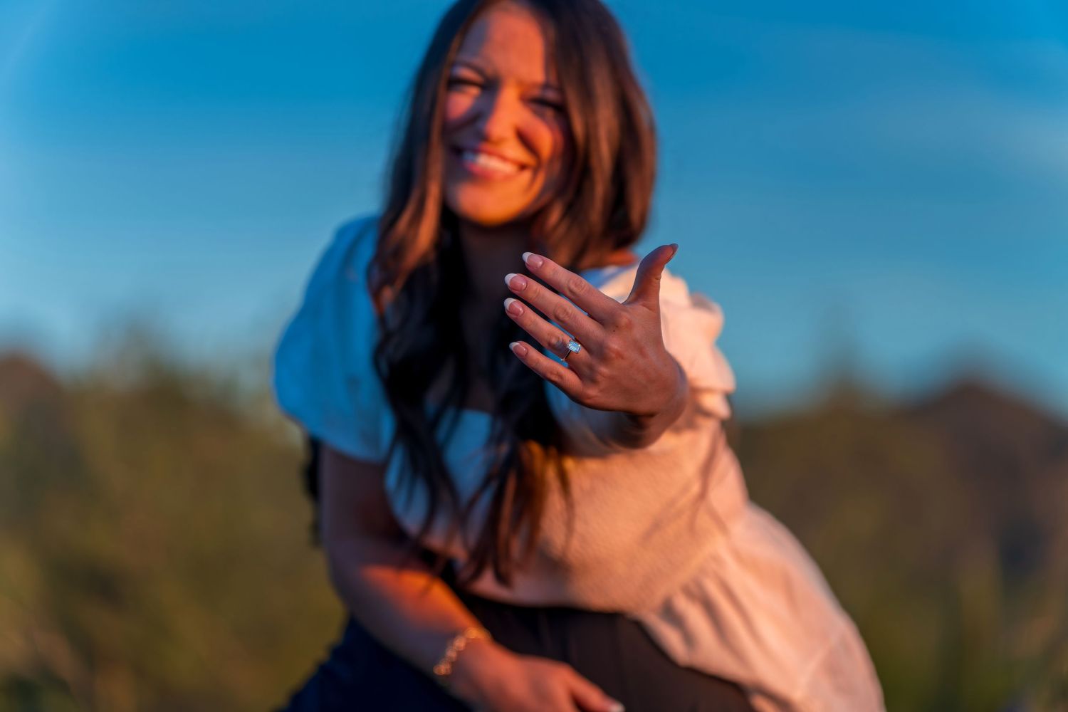 A couple embraces while standing on an outdoor deck with desert scenery.