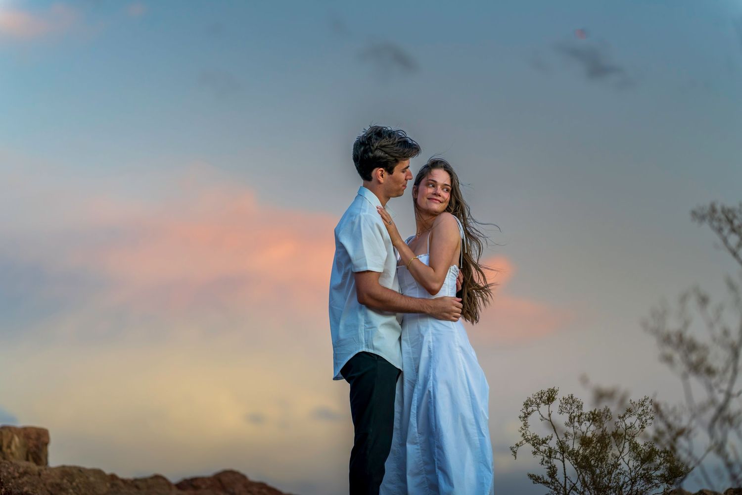 A romantic sunset photoshoot featuring a couple in complementary blue and white outfits.