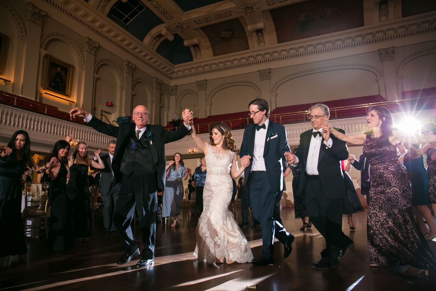 Joyful Greek wedding party dances together in an elegant grand ballroom during a lively wedding reception, Mechanics Hall, Worcester, MA