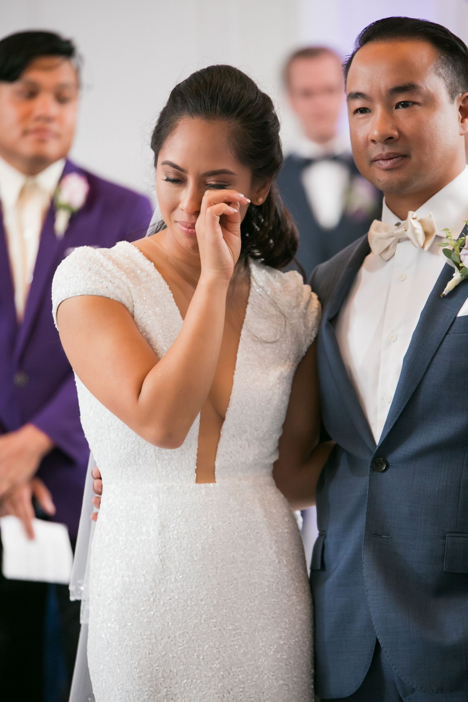 Emotional bride wipes tears beside groom in blue suit during heartfelt wedding ceremony, Courtyard by Marriott Boston Downtown, Boston, MA