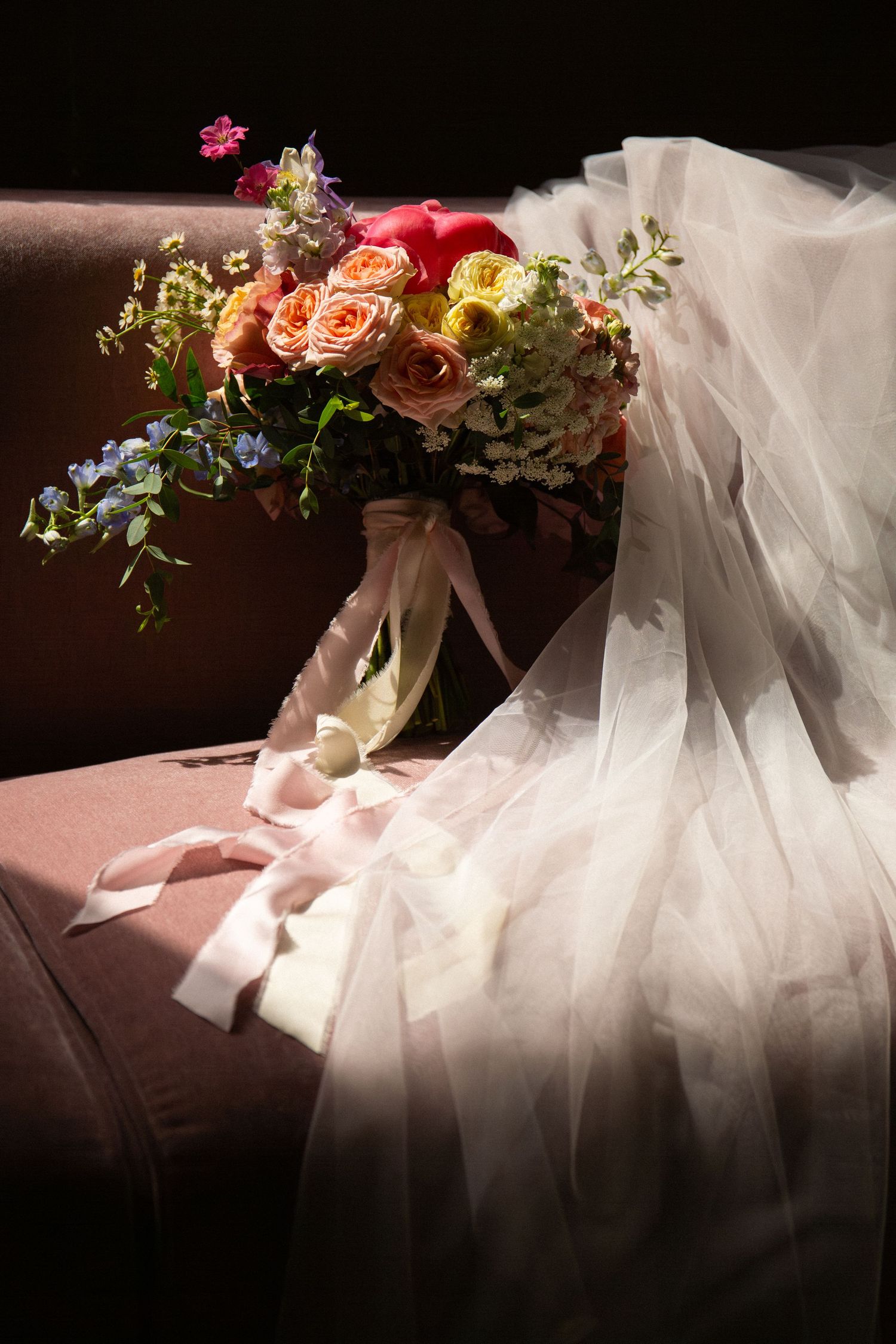 Colorful bridal bouquet of roses and wildflowers rests on a sofa beside a flowing white wedding veil, Grove at Briar Barn Inn, Rowley, MA