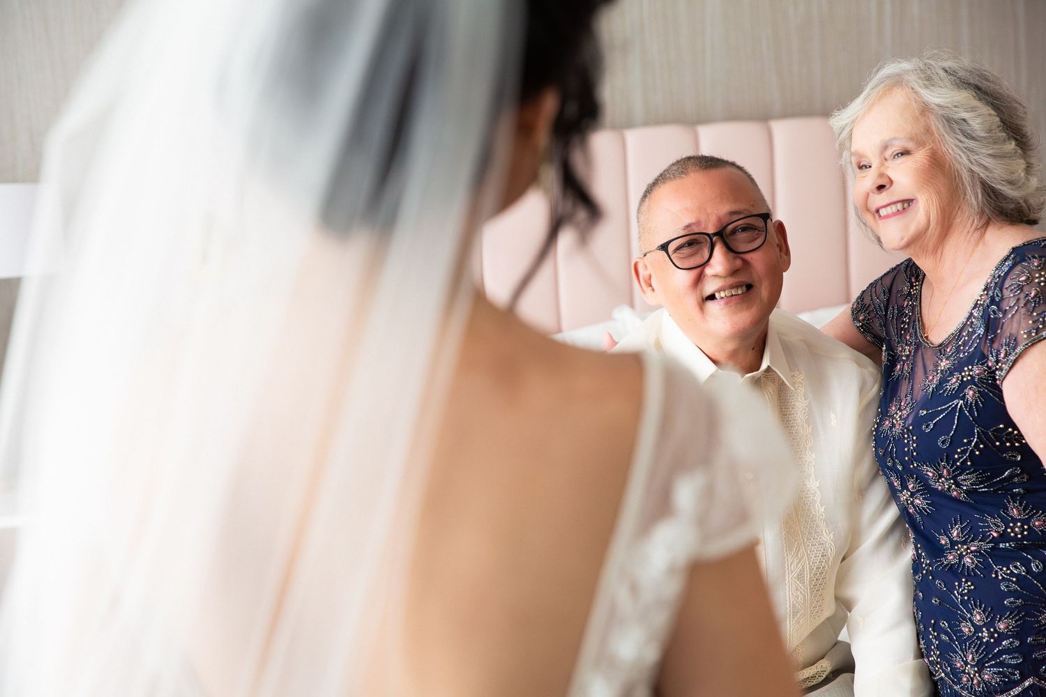 Proud parents smiling at bride in wedding dress during emotional first look, The Colonnade Hotel, Boston, MA