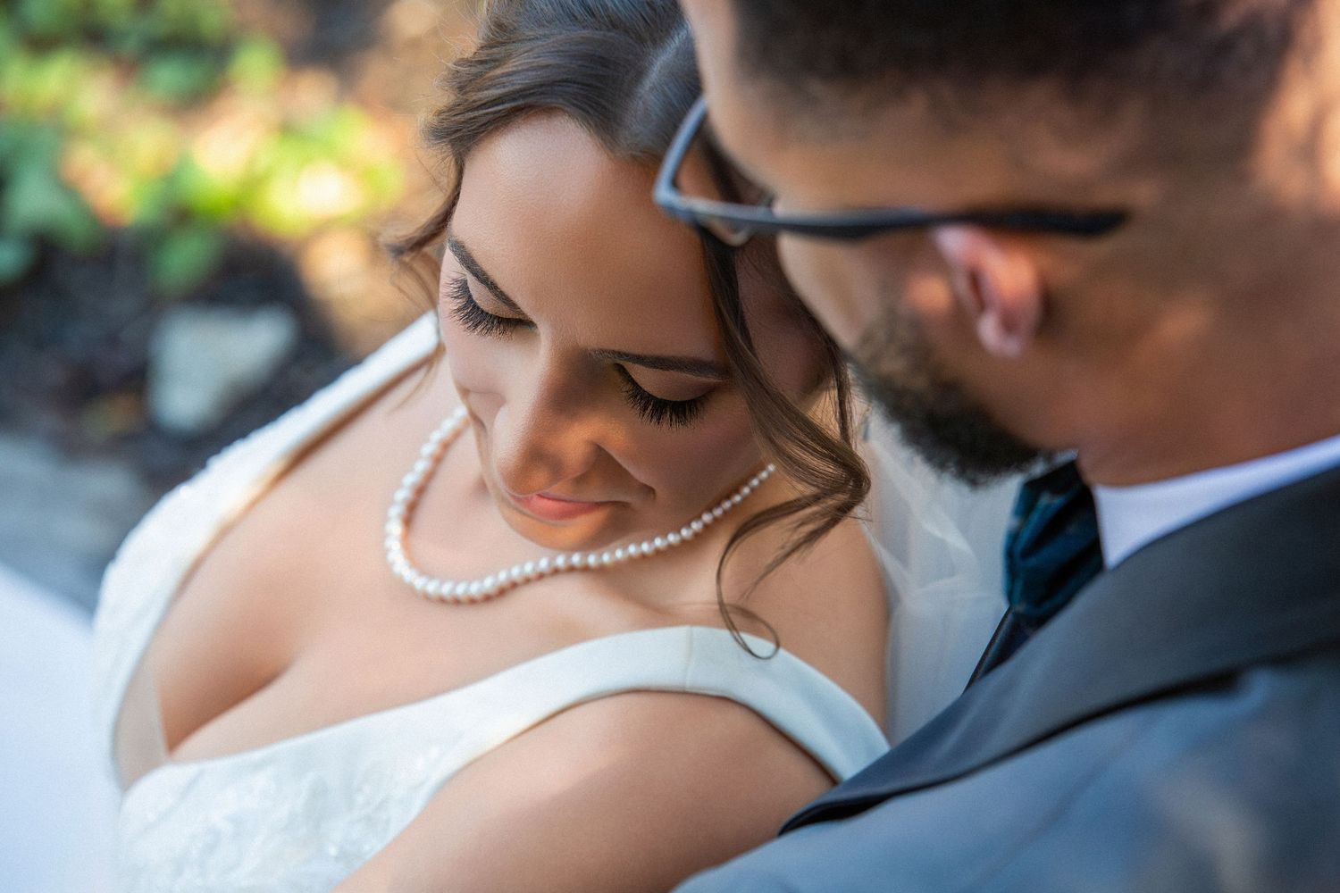 Close-up of bride wearing pearl necklace leaning into groom in soft natural light, The Red Lion Inn, Cohasset, MA