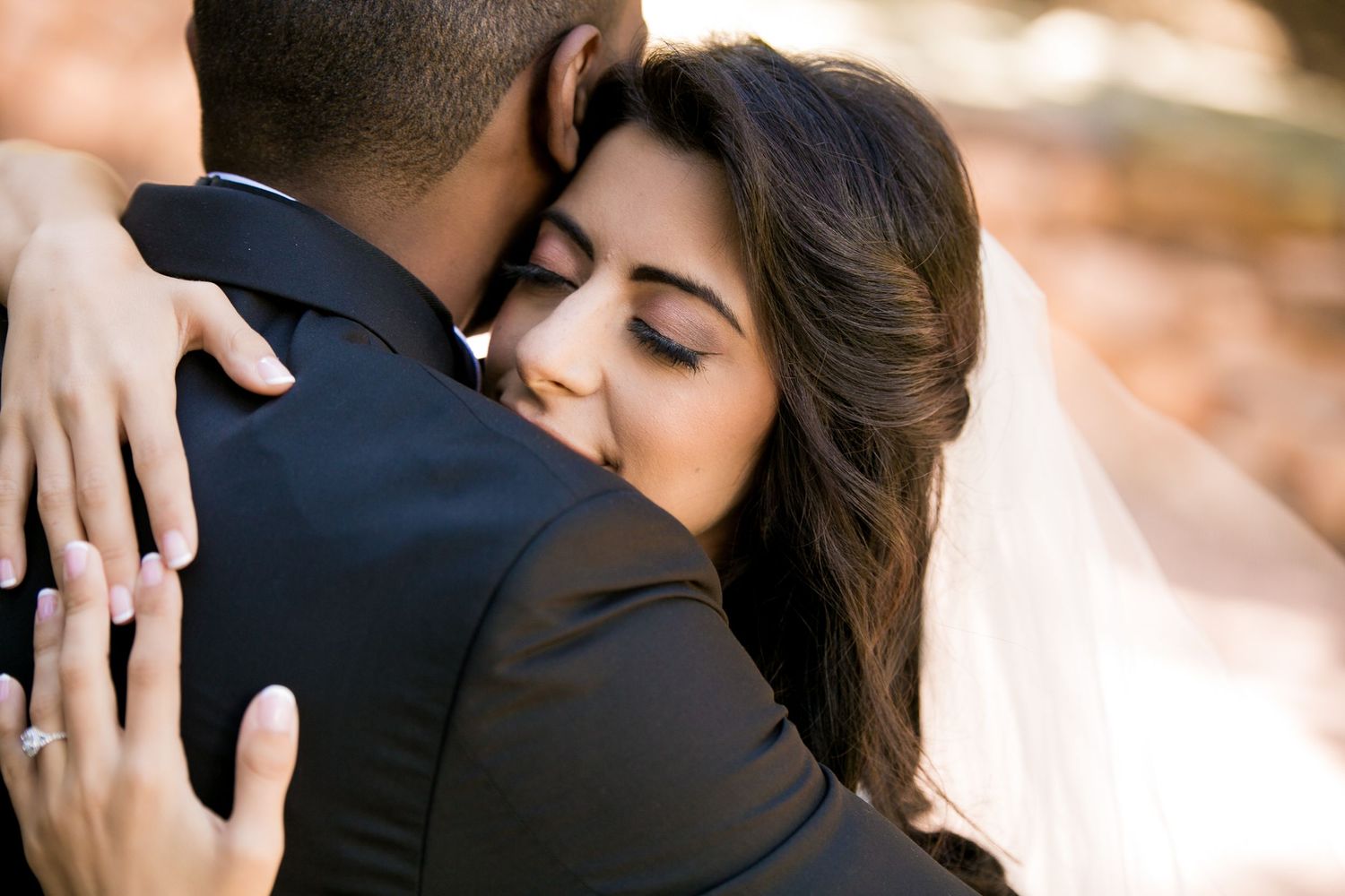 Bride in veil embraces groom tenderly in warm outdoor autumn wedding portrait,  Mandarin Oriental Boston, Boston, MA