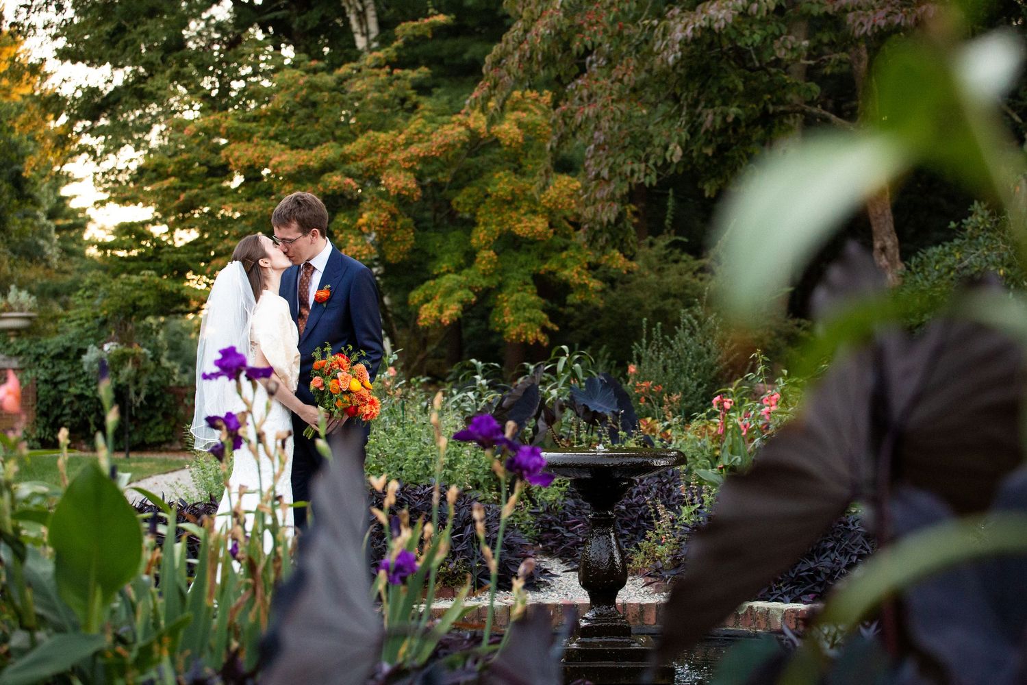 Bride and groom share intimate moment in colorful garden with fountain centerpiece,  The Bradley Estate, Canton, MA