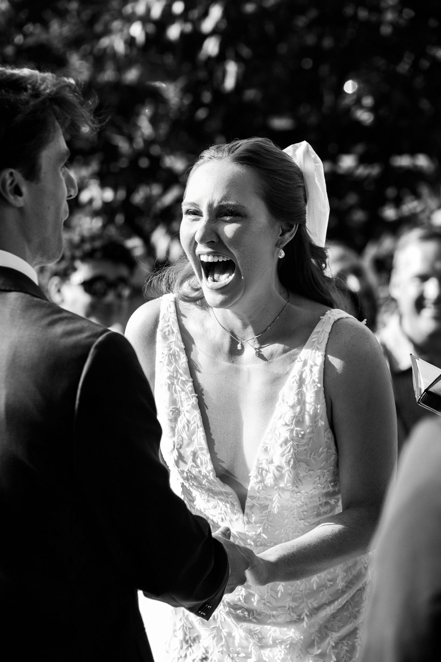 Joyful bride laughing with groom during outdoor wedding ceremony captured in black and white, Grove at Briar Barn Inn, Rowley, MA
