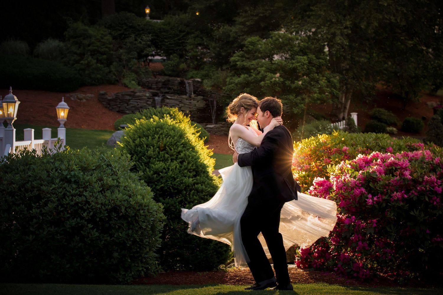 Groom lifting bride in a lush garden at dusk with colorful blooming flowers, Castleton Banquet and Conference Center, Windham, NH