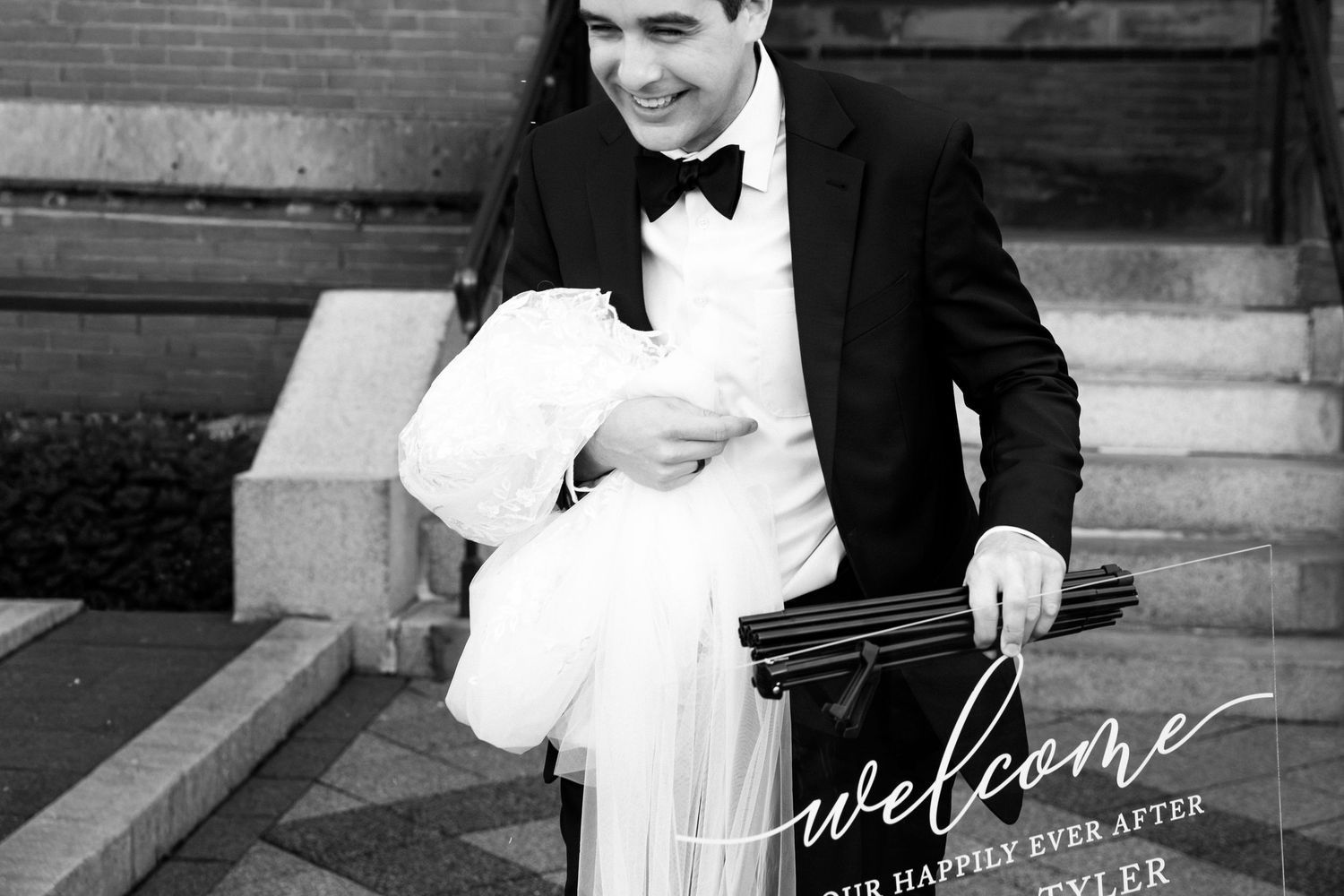 Groom in tuxedo carries wedding sign in black and white, Xenia Helix Photography, Boston, MA