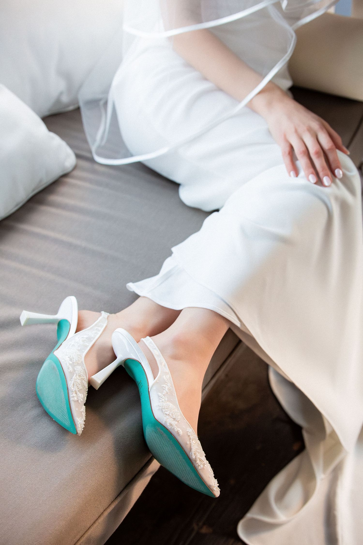 Bride in white dress seated on a sofa wearing lace and turquoise heeled wedding shoes, Grove at Briar Barn Inn, Rowley, MA