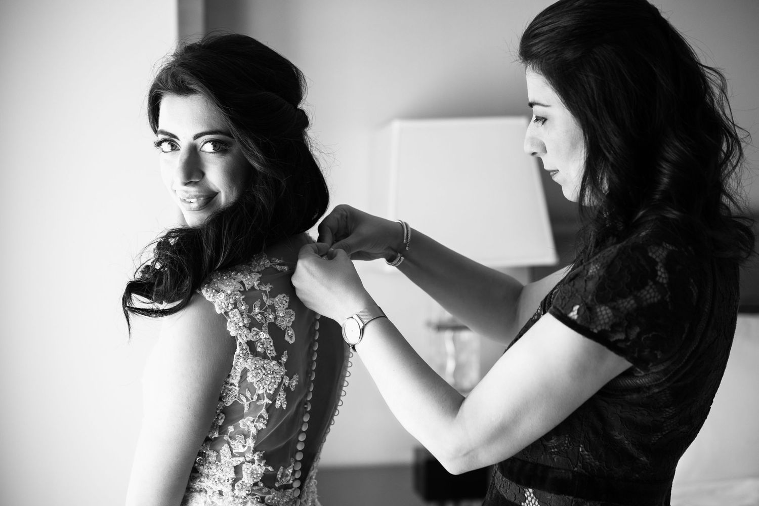 Black and white photo of mom helping a bride fasten her beaded wedding dress before the ceremony, Mandarin Oriental Boston, Boston, MA