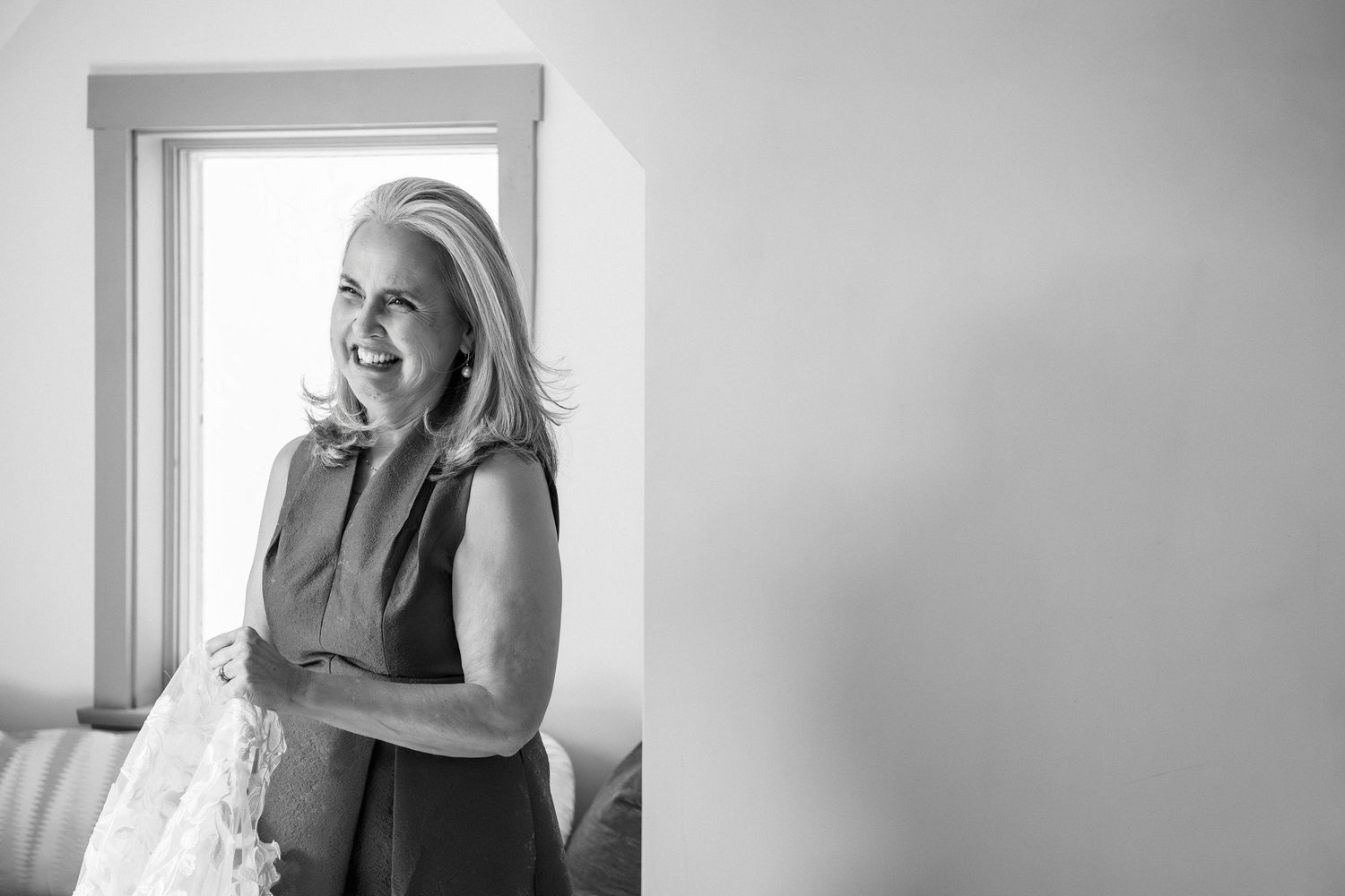 Mother of the bride smiling while holding a bridal veil near a sunlit window, Grove at Briar Barn Inn, Rowley, MA