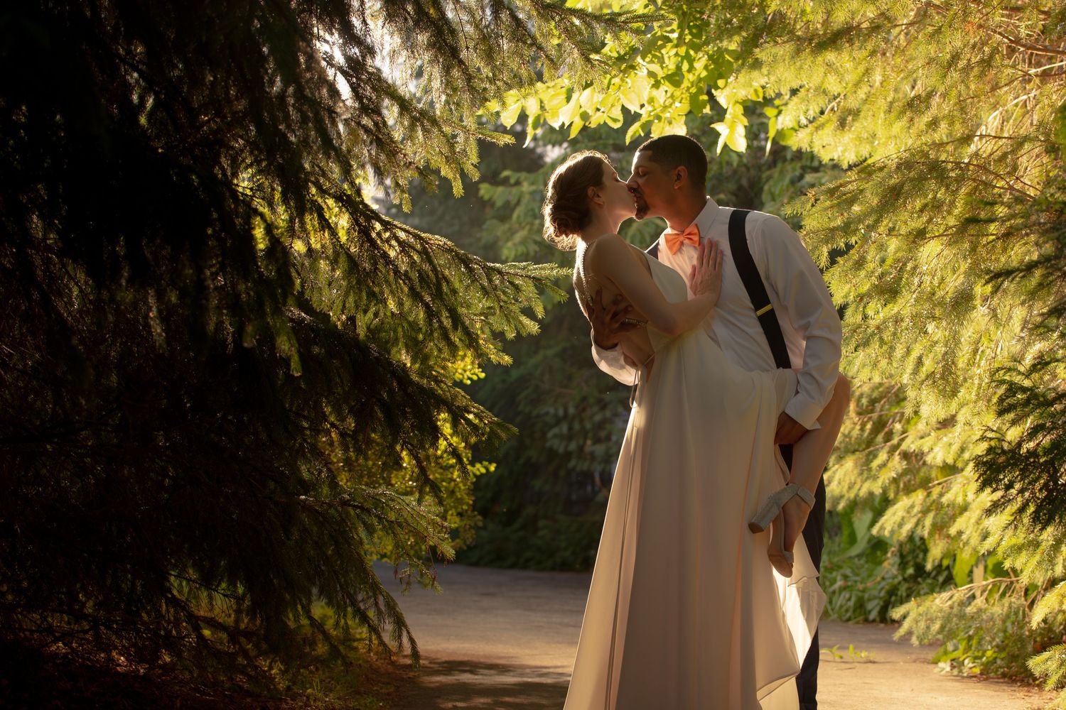 Wedding couple kissing tenderly beneath lush green trees in warm sunlight, Groveland Fairways, Groveland, MA