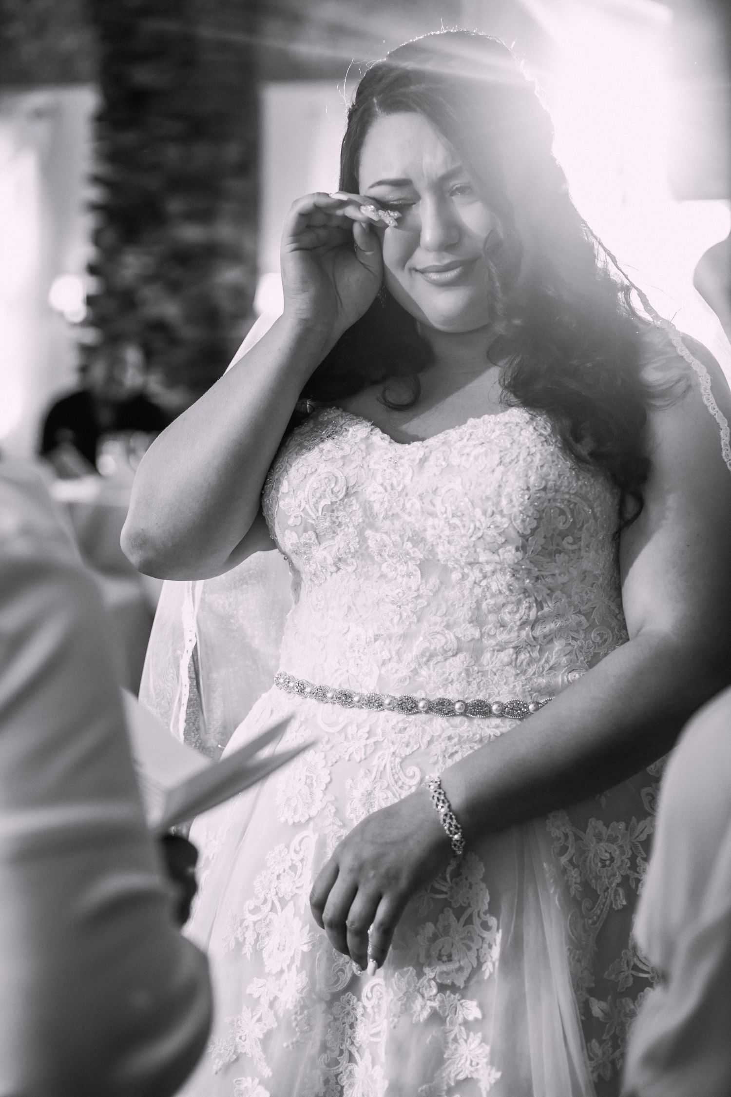 Black and white photo of Jenyka, a tearful bride wiping her eye during an emotional wedding moment, Monoosnock Country Club, Leominster, MA