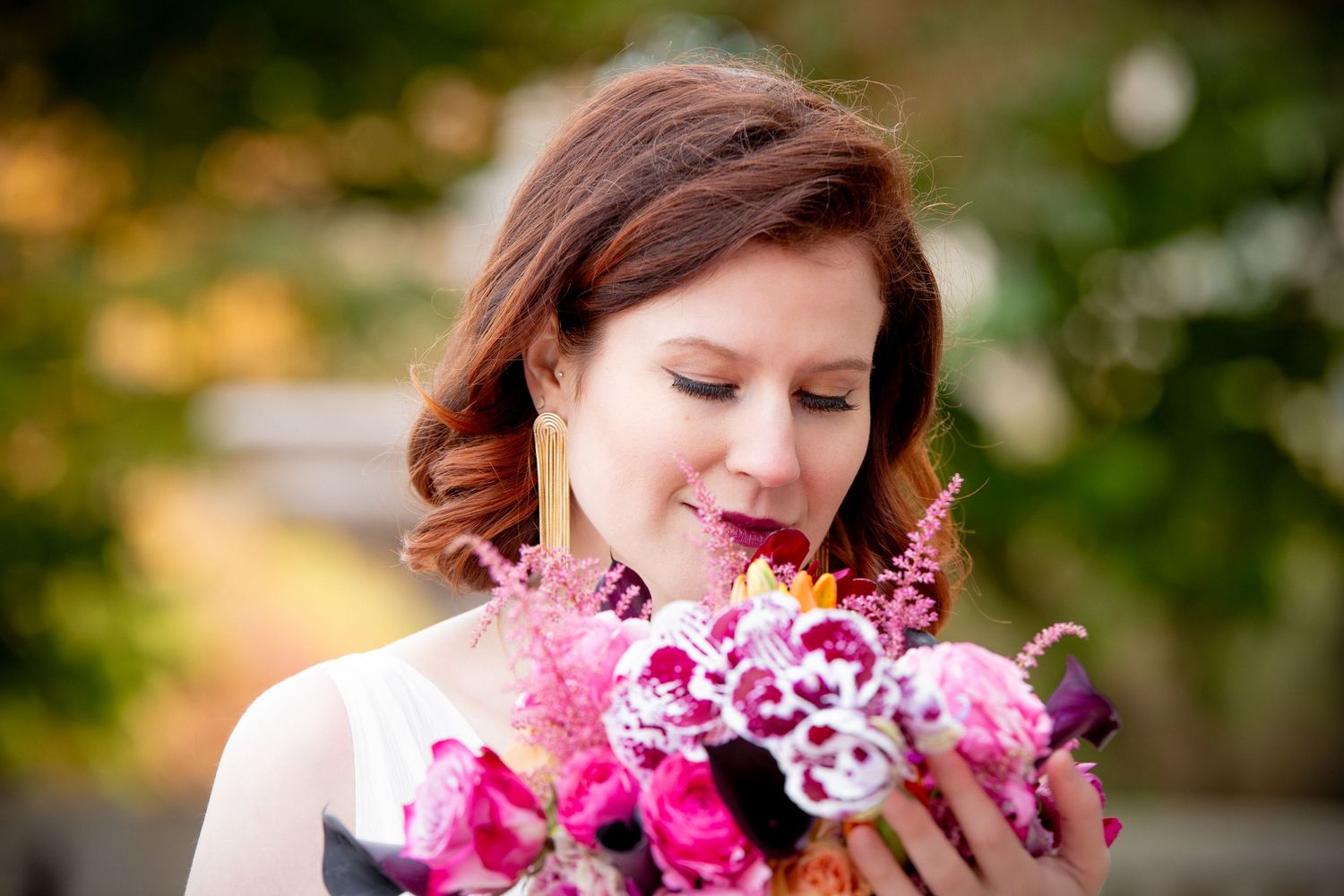 Red-haired bride smelling vibrant pink and magenta wedding bouquet with soft bokeh background, Robbins Memorial Town Hall, Arlington, MA