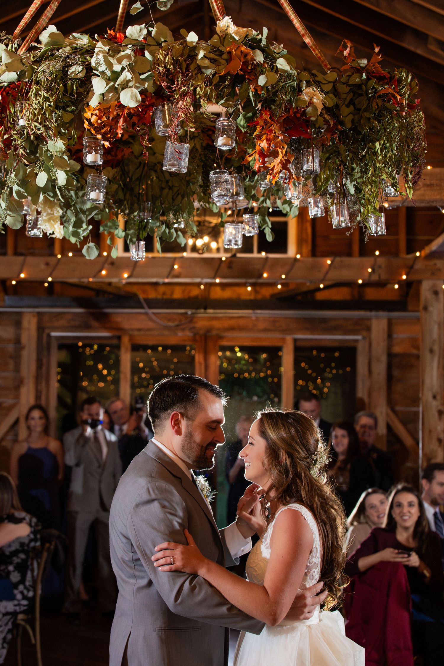 Bride & groom share first dance under stunning floral chandelier with hanging lanterns in rustic venue, Barn at Bradstreet Farm, Rowley, MA
