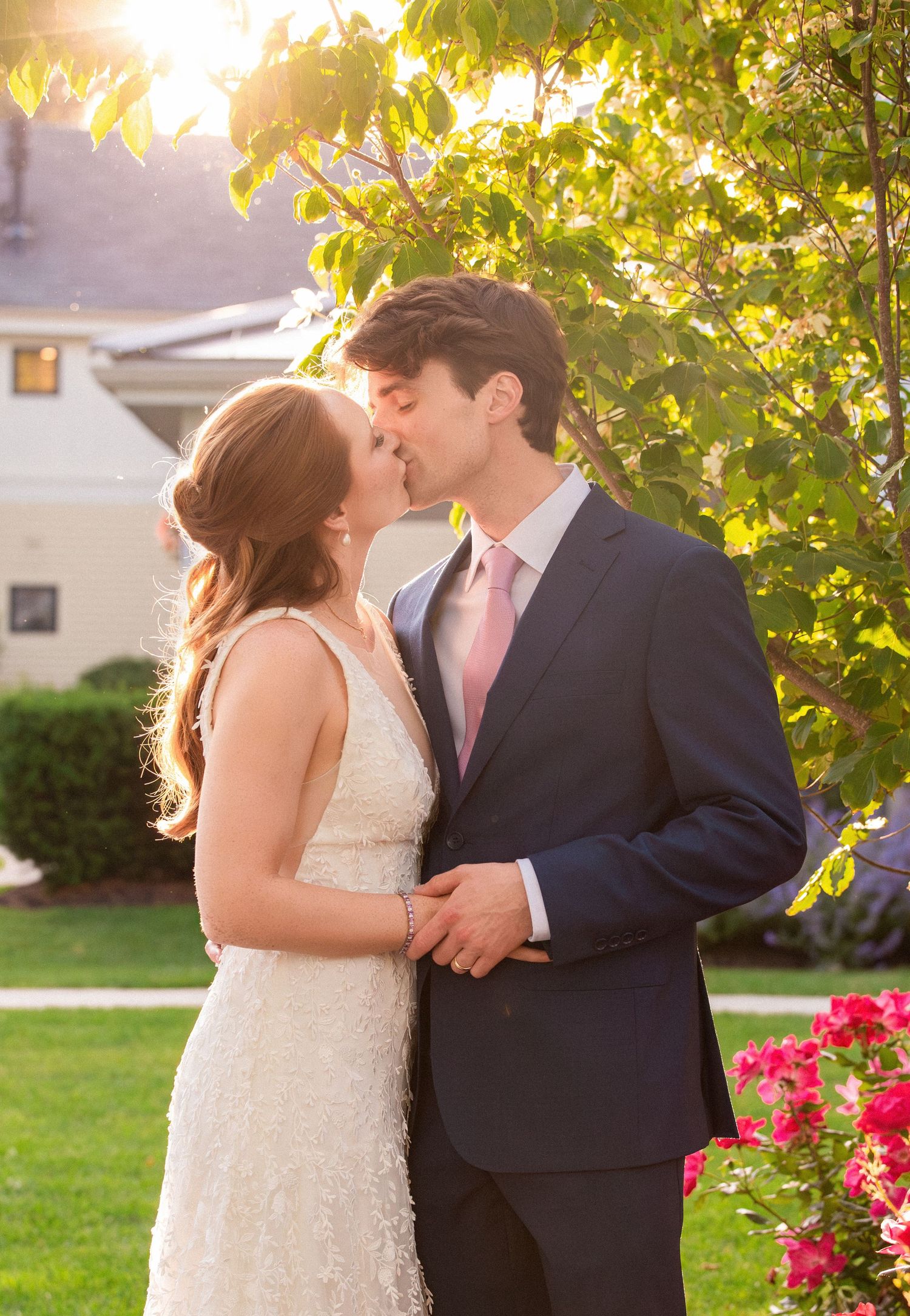 Bride and groom sharing a romantic kiss in golden sunset light surrounded by lush greenery, Grove at Briar Barn Inn, Rowley, MA