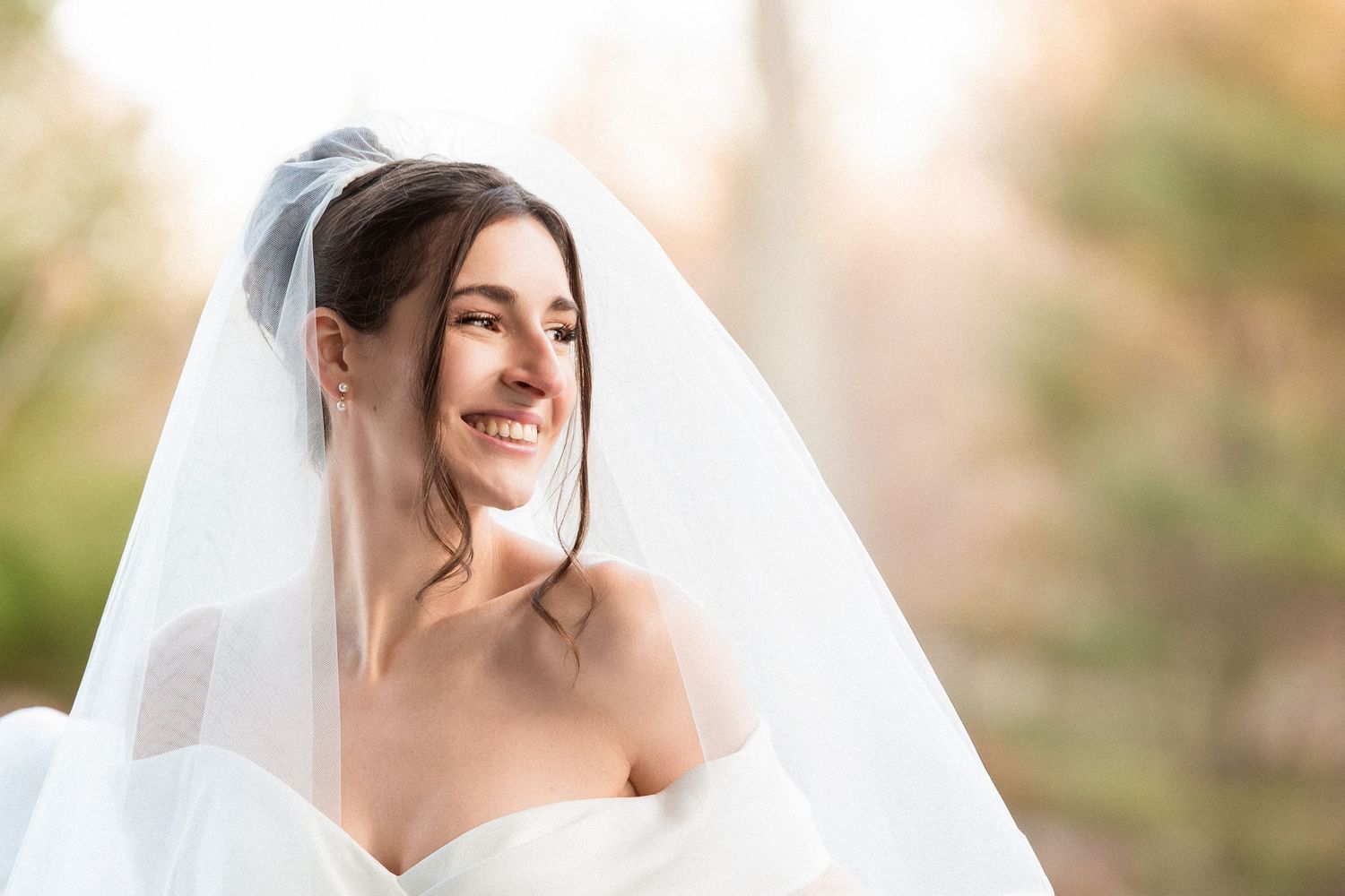Smiling bride in a strapless wedding dress and veil poses outdoors in soft natural light, Grove at Briar Barn Inn, Rowley, MA