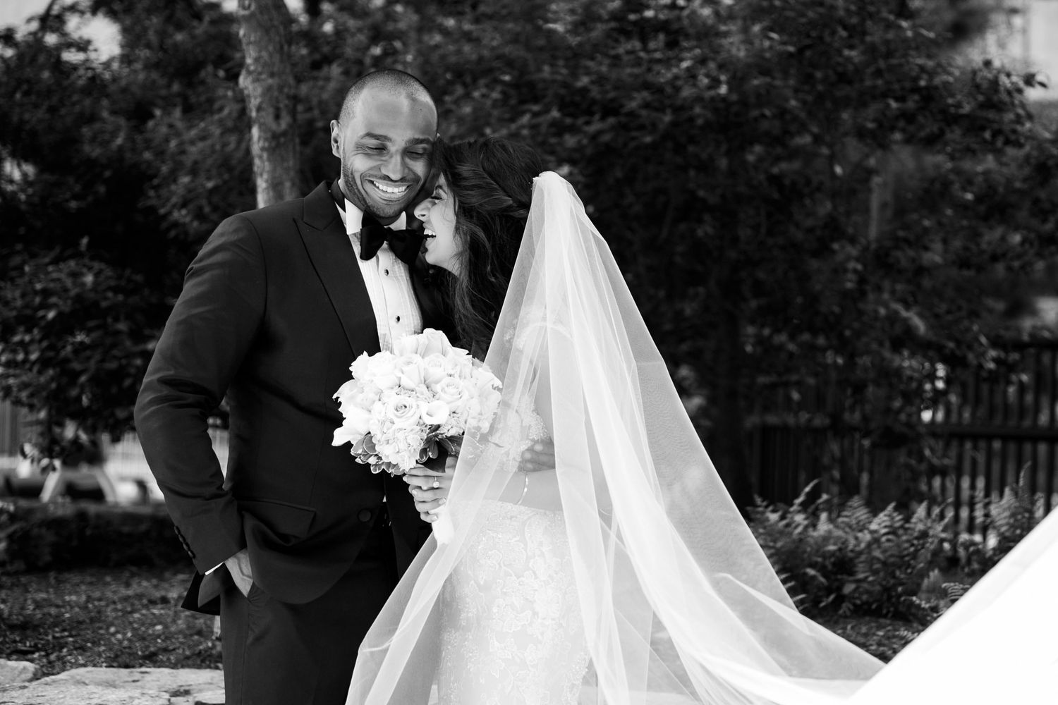 The bride and groom share a laugh as the bride leans on his shoulder in a black-and-white wedding portrait,  Mandarin Oriental Boston, MA